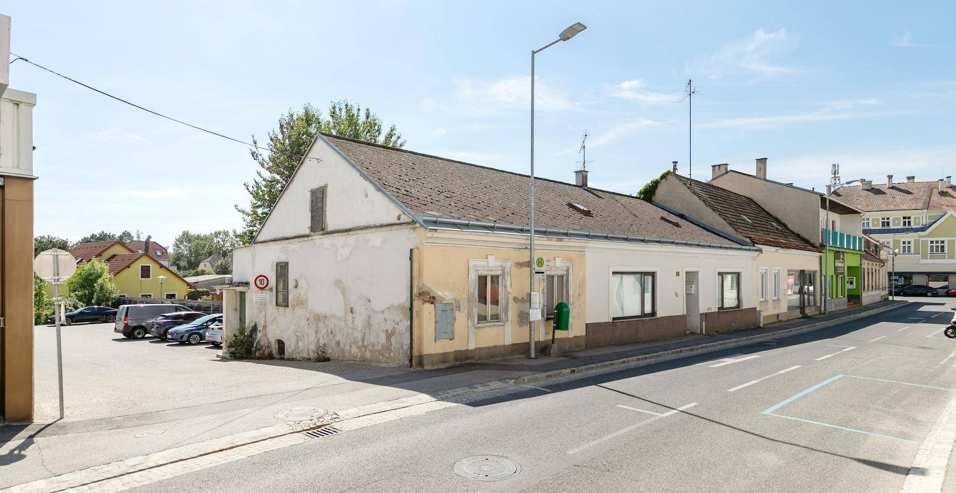 Seitenansicht des Gebäudes mit angrenzendem Parkplatz und Blick auf die Straße.