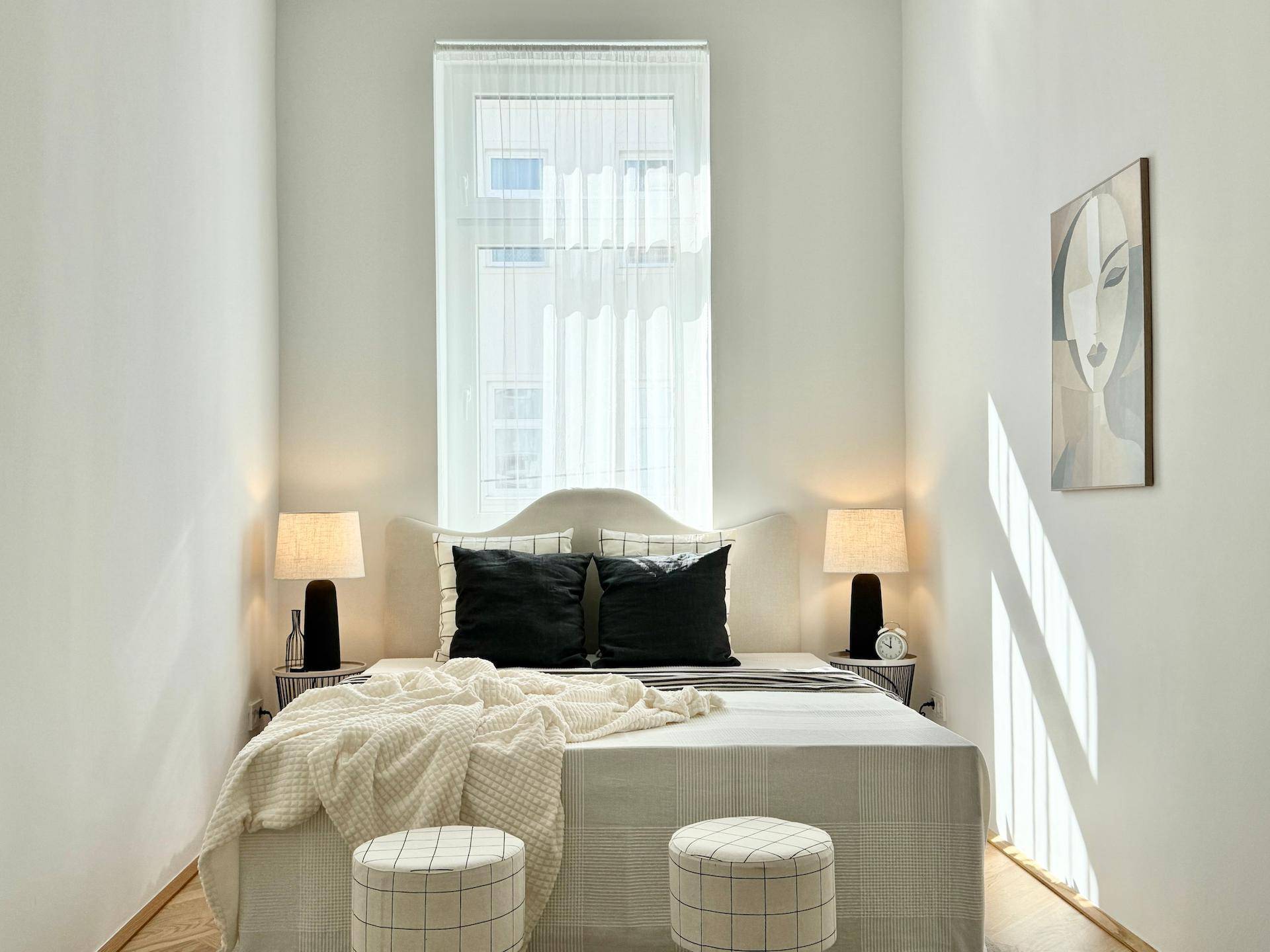 Gemütliches Schlafzimmer mit großem Fenster, hellem Interieur und zwei Nachttischen.
