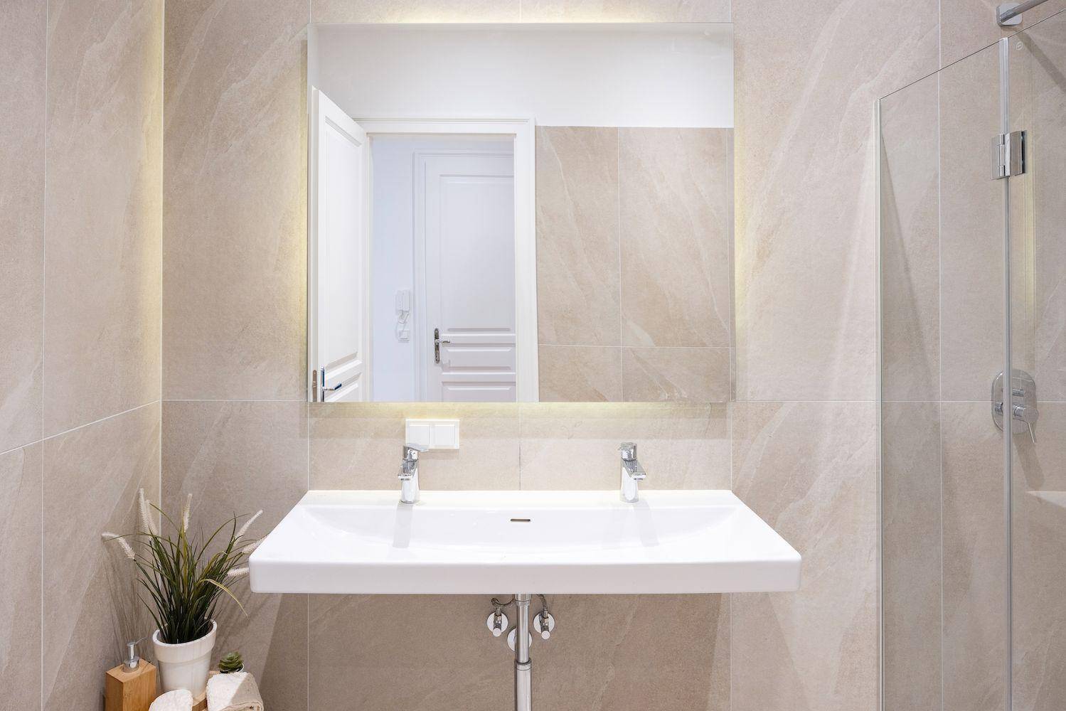 Modernes Badezimmer mit Doppelwaschbecken, großem Spiegel und begehbarer Dusche.
