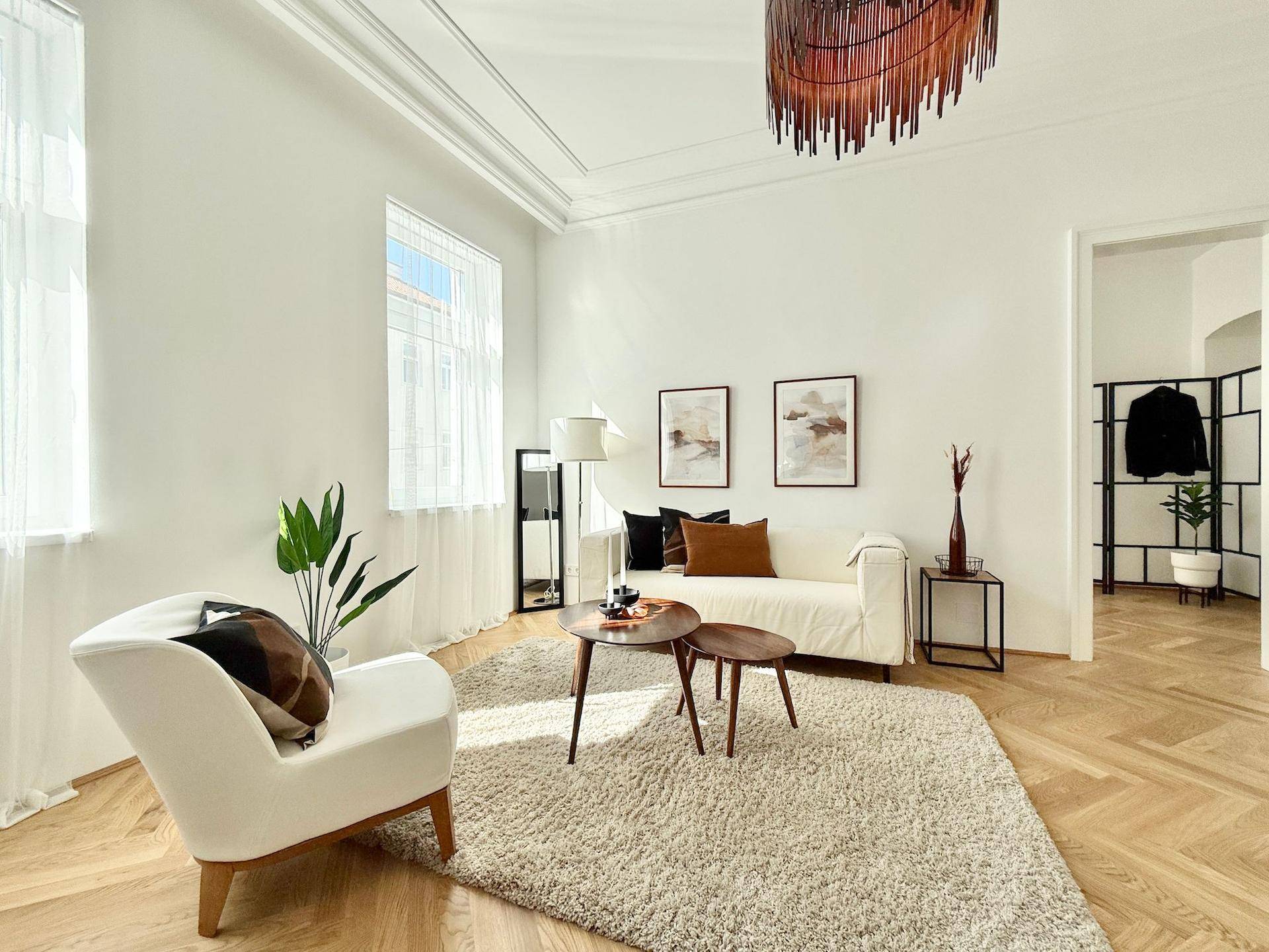 Lichtdurchflutetes Wohnzimmer mit hohen Decken, elegantem Parkett und stilvoller Dekoration.
