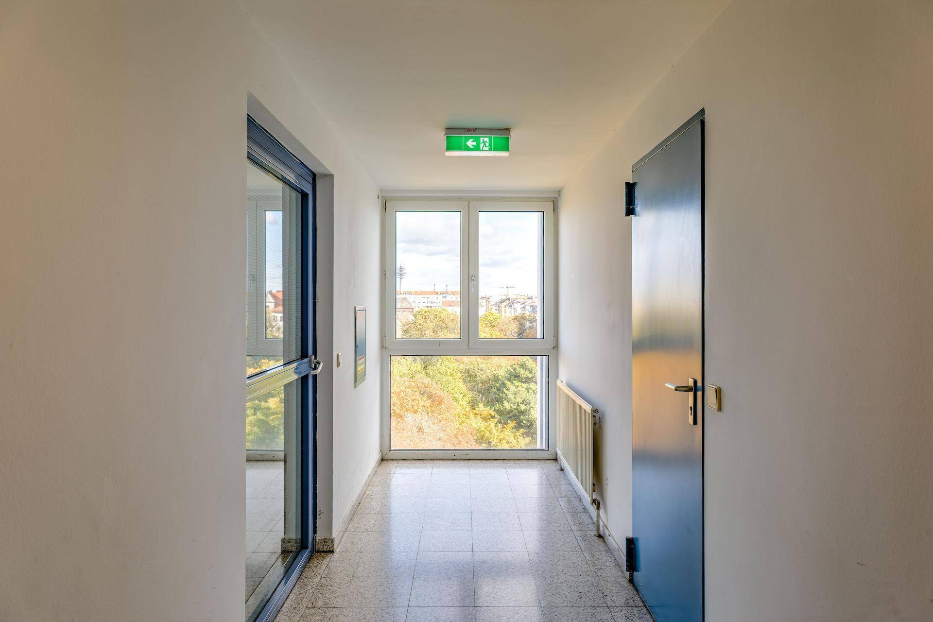 Heller Flur mit Fliesenboden und großem Fenster, das einen Blick ins Grüne bietet.