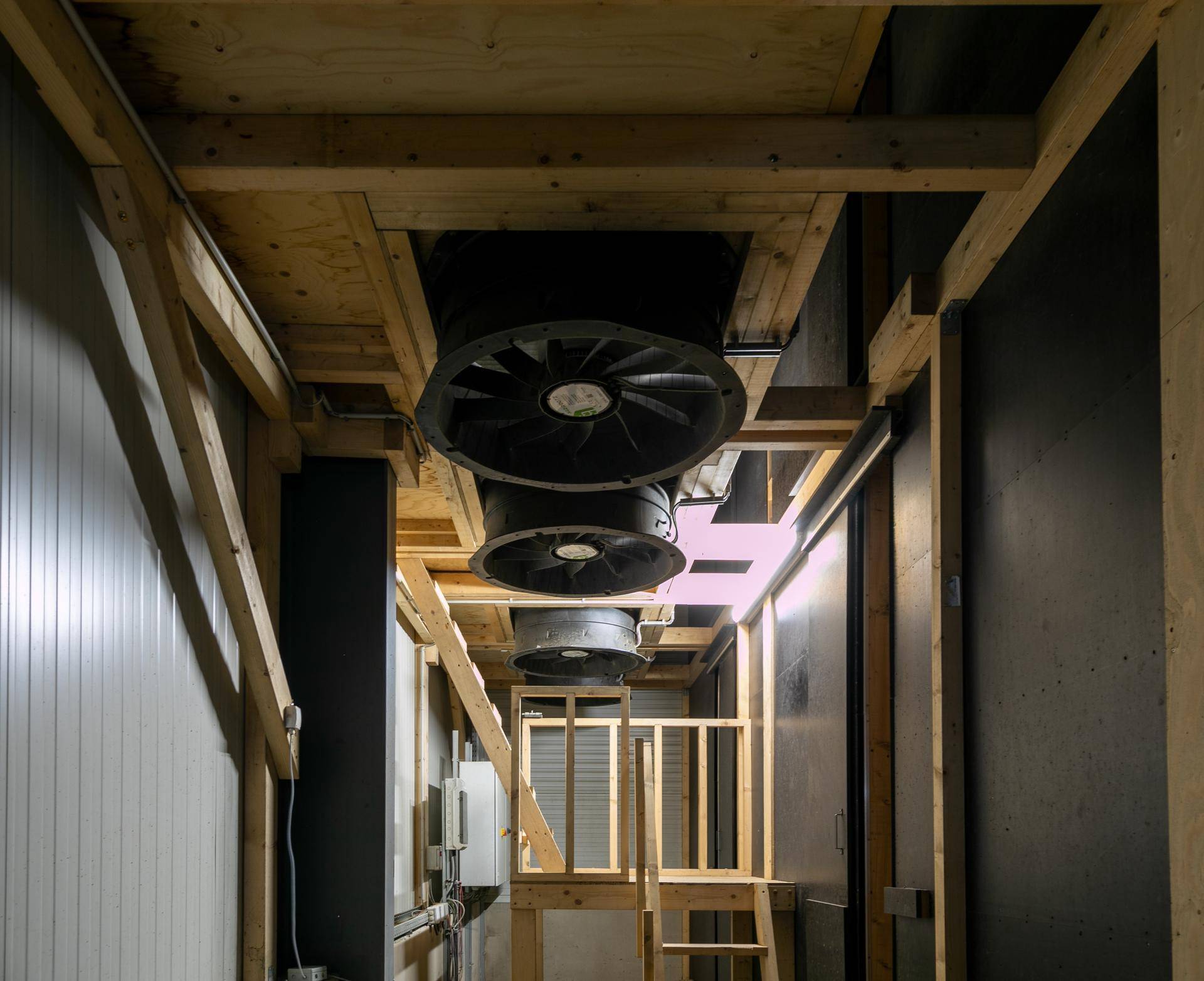 Technischer Bereich mit großen Lüftungsventilatoren und Holzkonstruktionen, die die Luftzirkulation gewährleisten.