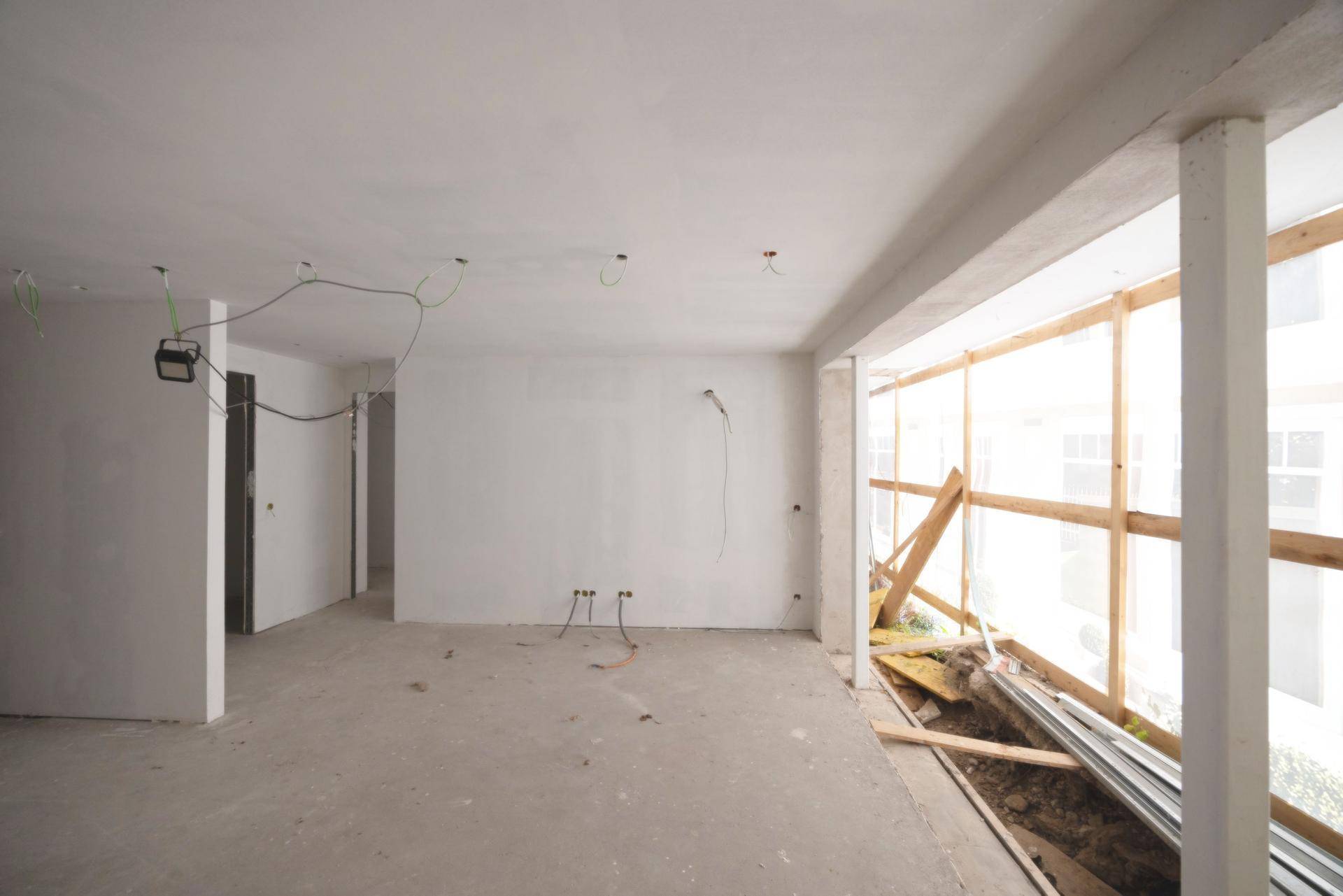 Heller Rohbau mit großer Fensteröffnung, die viel Tageslicht in den Raum lässt.