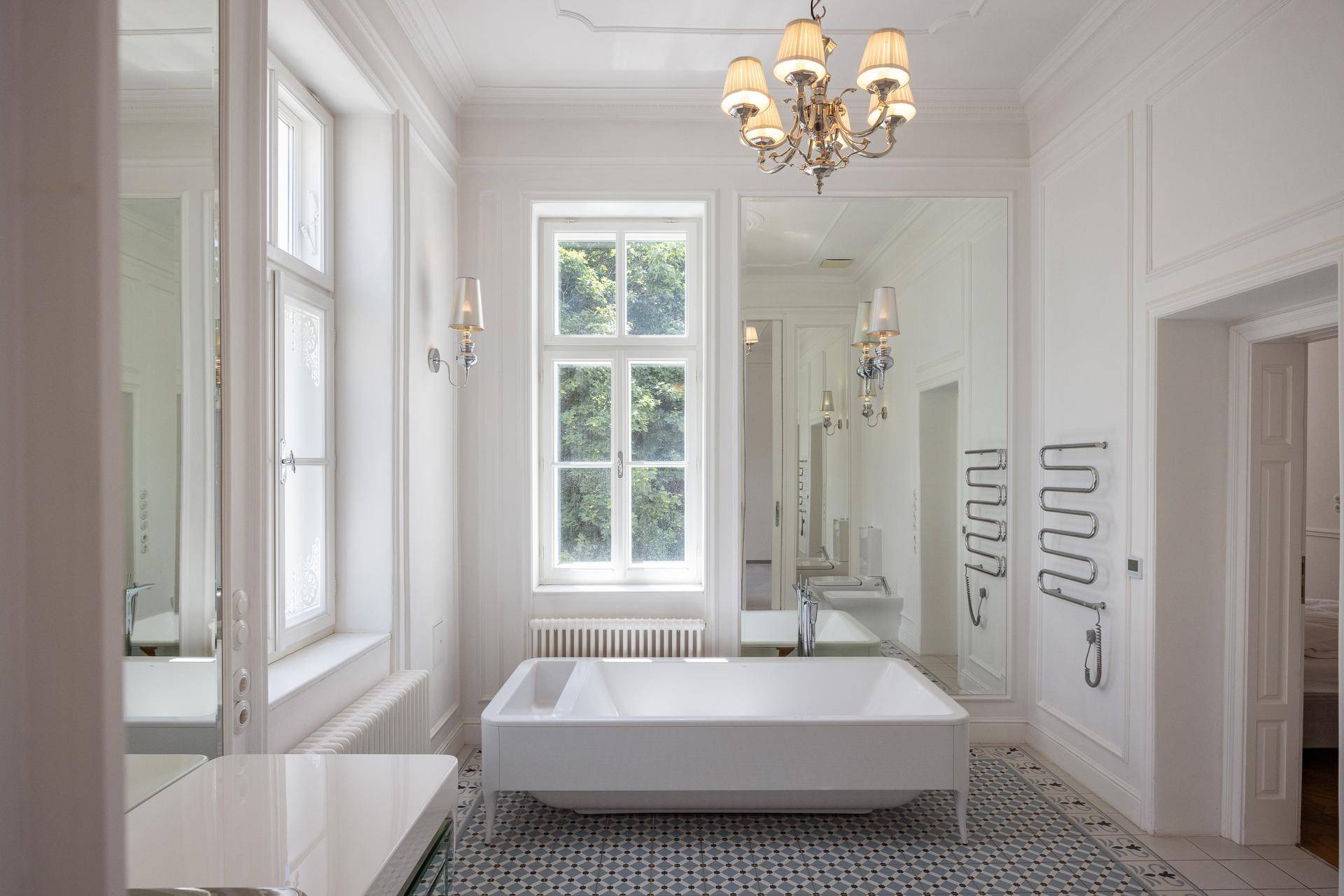 Luxuriöses Badezimmer mit freistehender Badewanne, großen Spiegeln und hohen Decken.