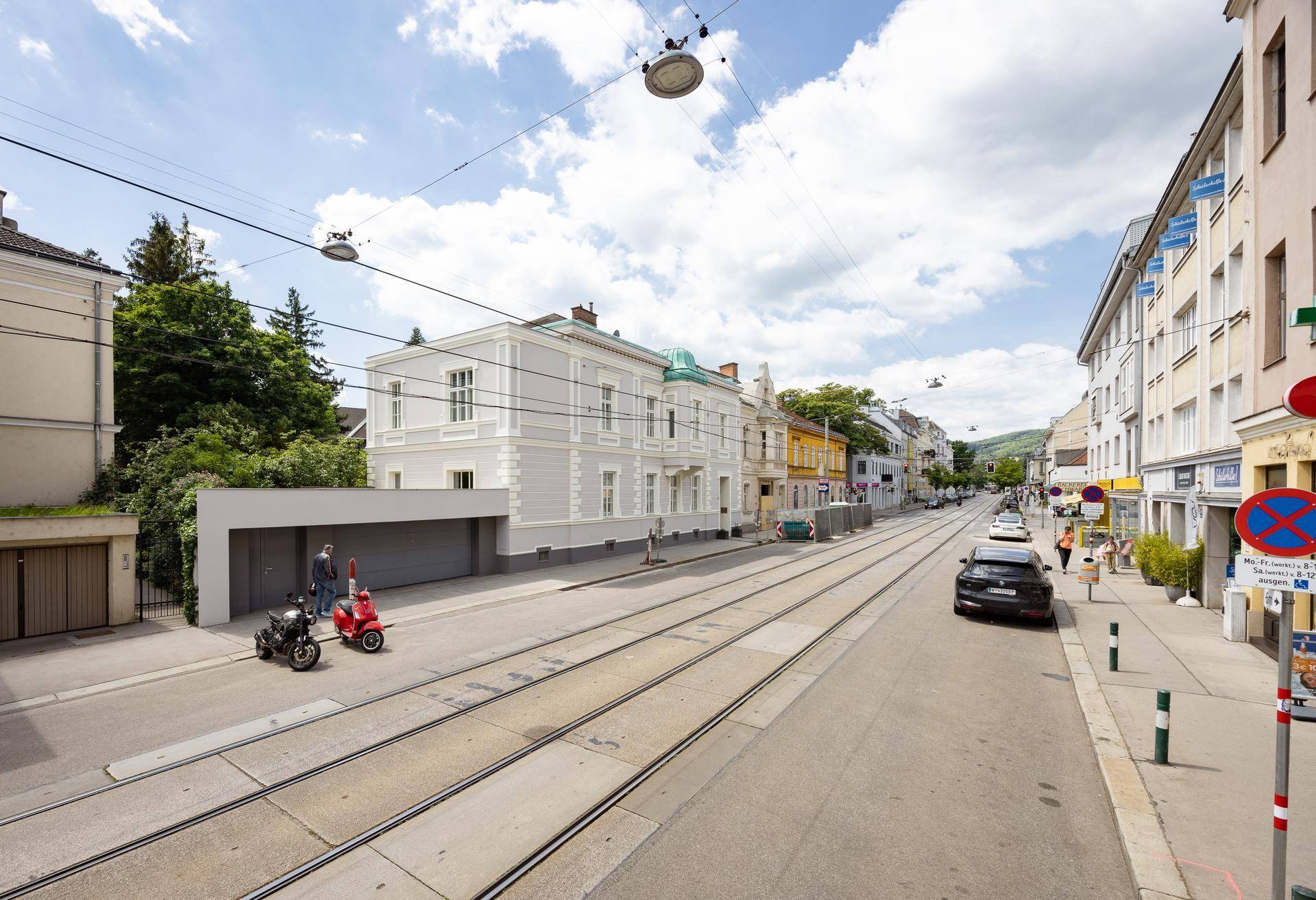 Weitläufige Ansicht des historischen Gebäudes an einer Straße mit Straßenbahnschienen.