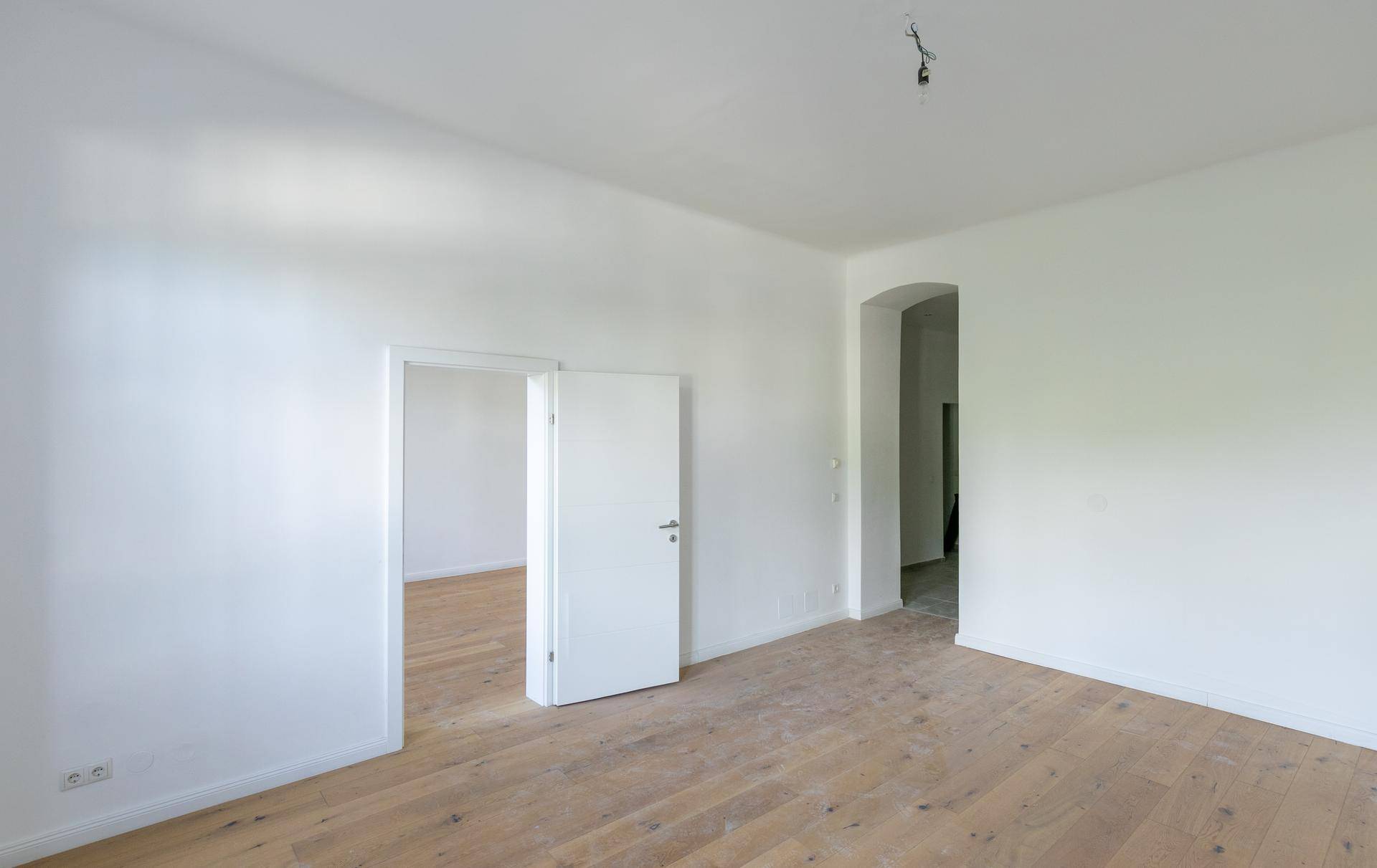 Geräumiges Zimmer mit hellem Holzboden und weiß gestrichenen Wänden, ideal für Wohnzwecke.
