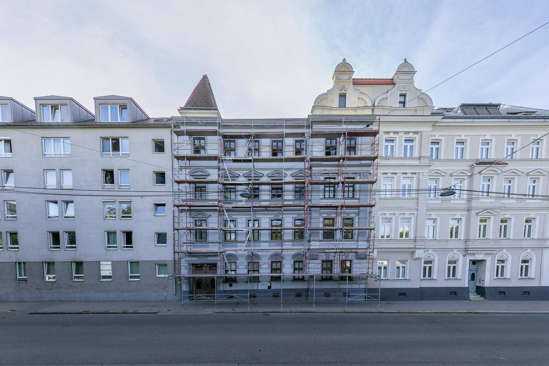 Historisches Gebäude mit Gerüst an der Fassade, umgeben von anderen Stadthäusern in der Stadt.