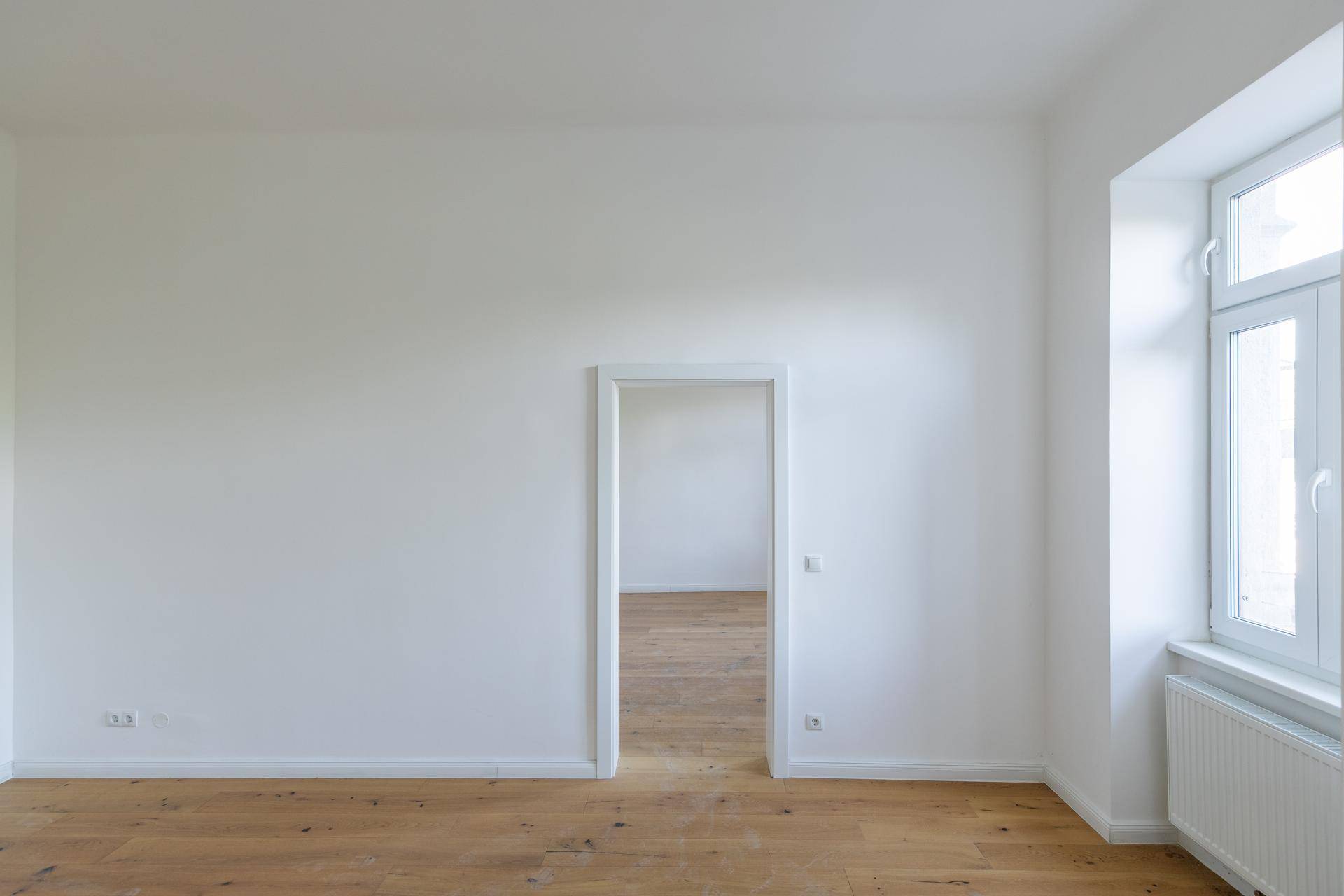 Heller Raum mit Holzboden und weißer Wand, bietet viel Potenzial für individuelle Einrichtung und Nutzung.