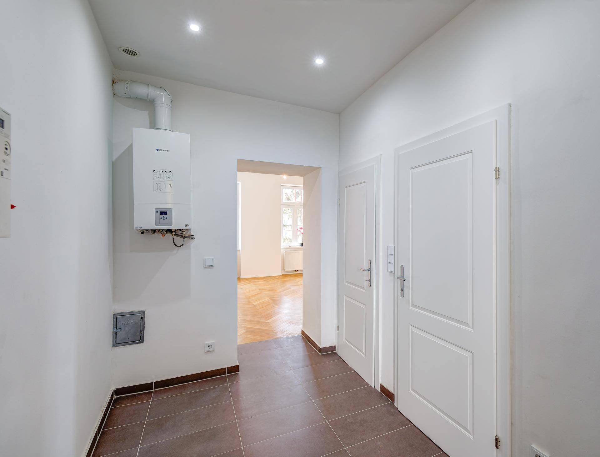 Flur mit Gastherme an der Wand und Zugang zu weiteren Zimmern, gefliestem Boden.