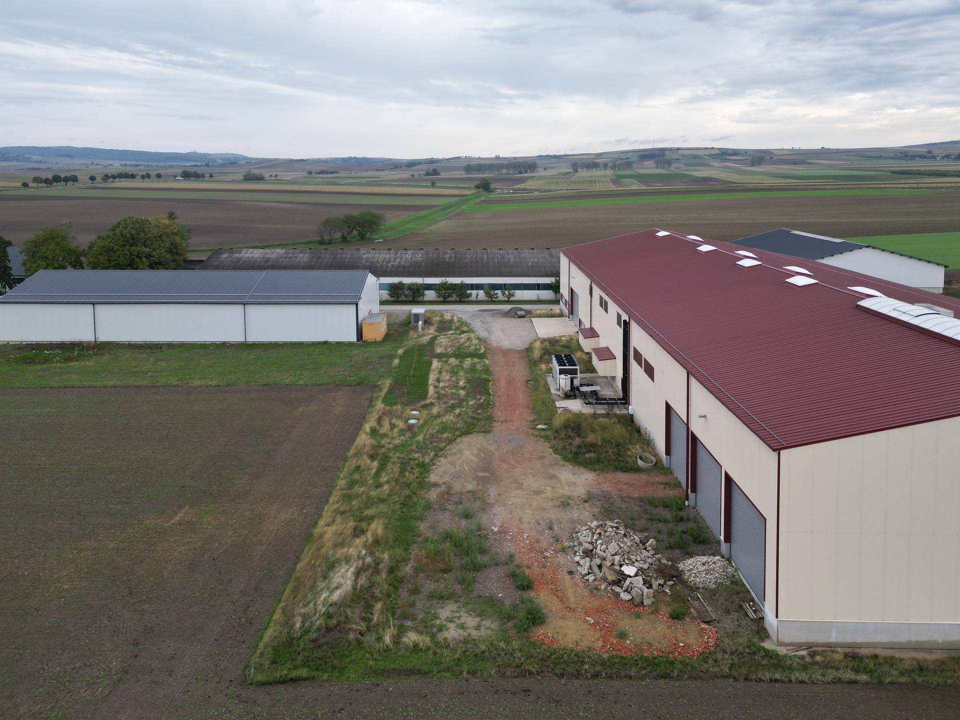 Panoramablick auf das Lagergebäude und die weite, grüne Landschaft mit weiteren Gebäuden in der Ferne.