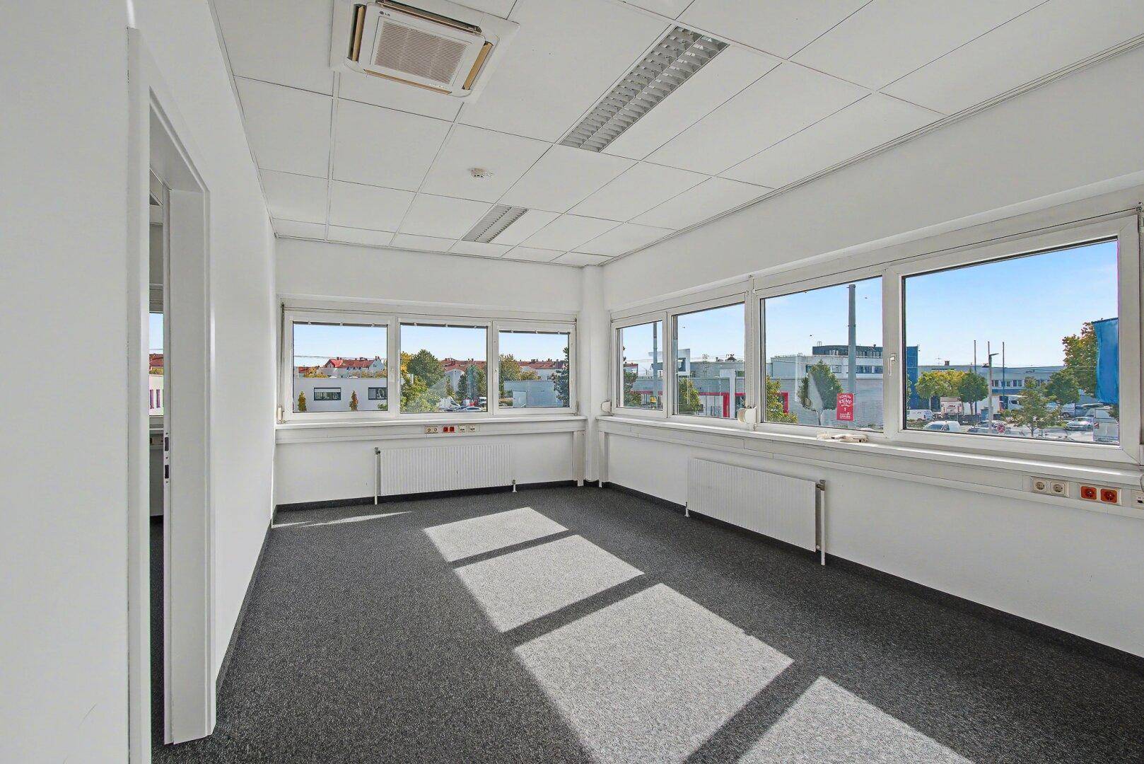 Geräumiges Büro mit Teppichboden, vielen Fenstern und weitem Blick über die Stadt.