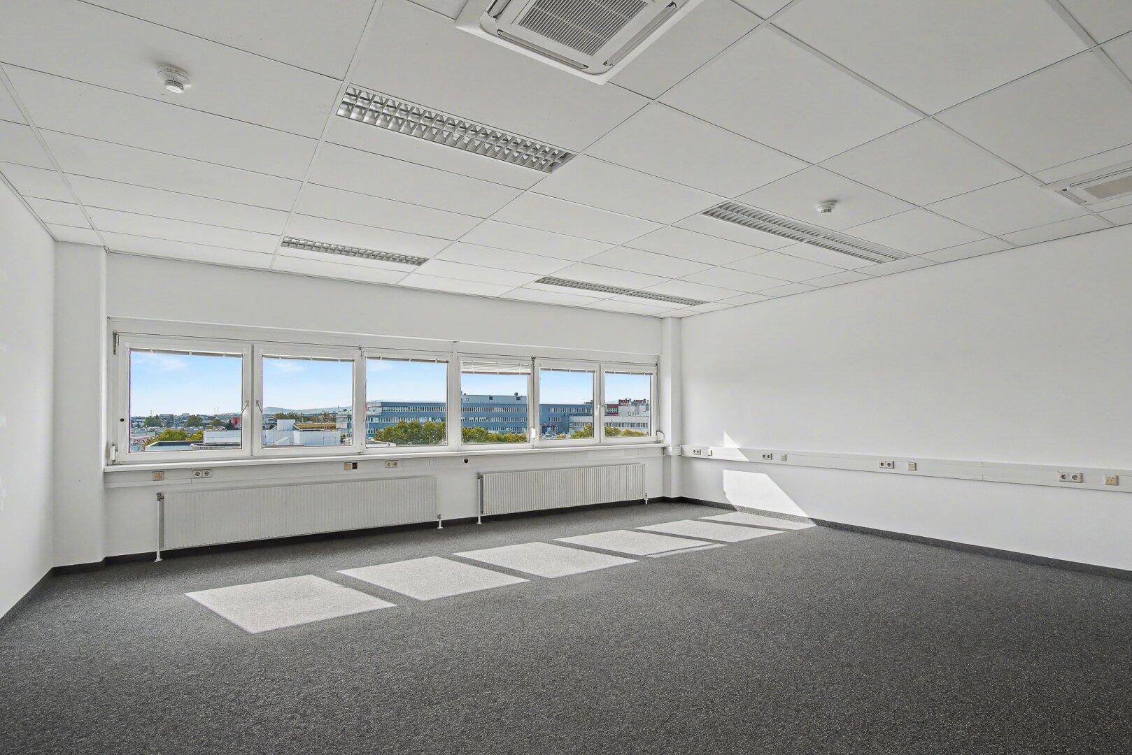 Geräumiges Büro mit Teppichboden, vielen Fenstern und weitem Blick über die Stadt.