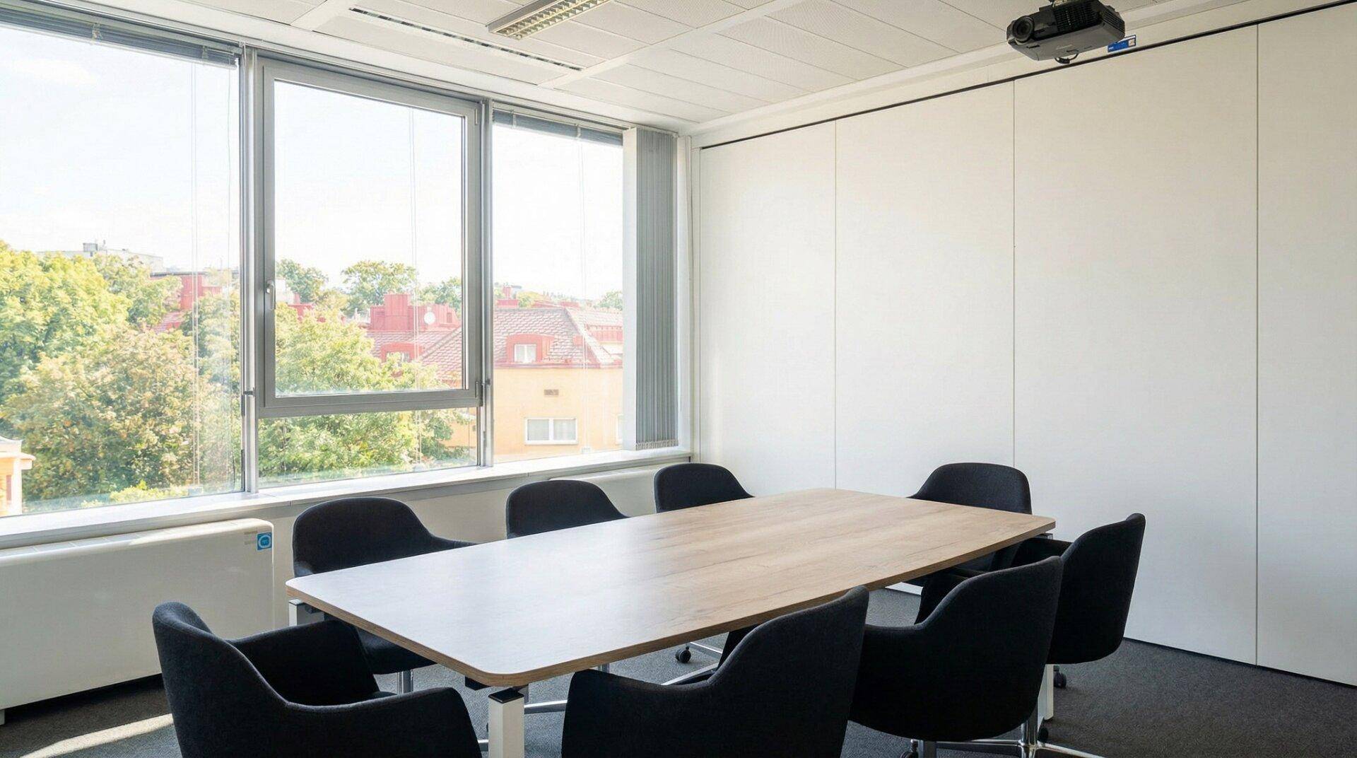 Heller Konferenzraum mit großem Holztisch, schwarzen Stühlen und weitem Blick durch große Fenster.