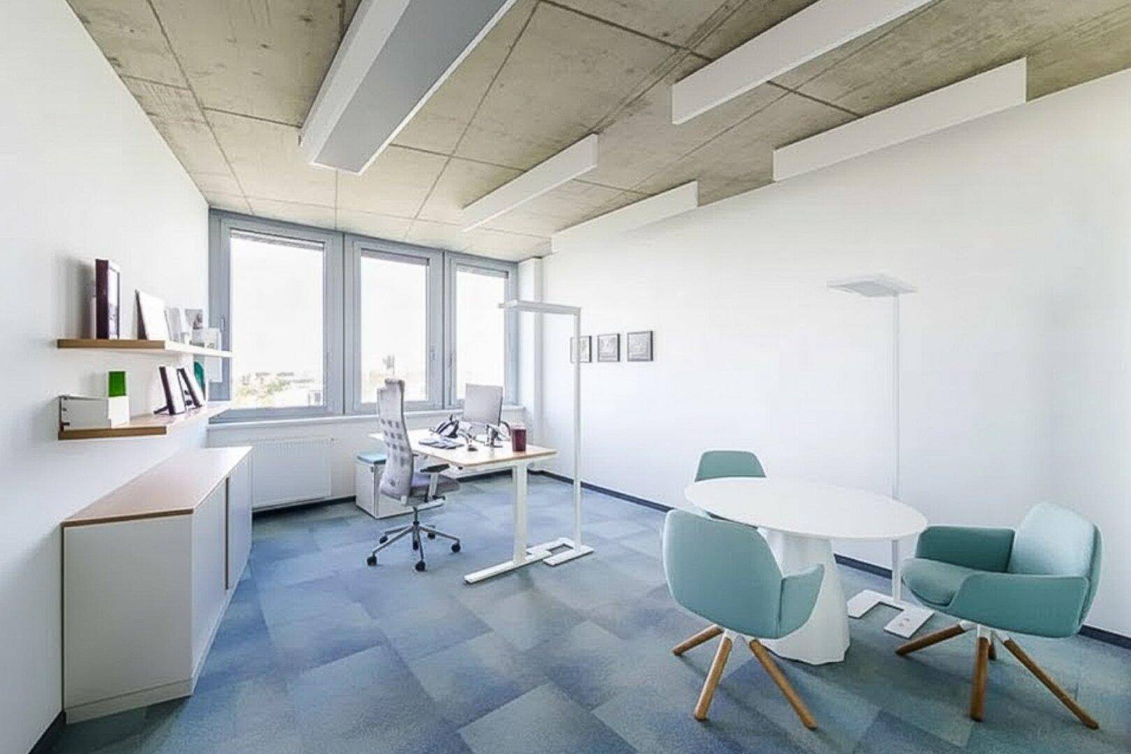 Helles Büro mit Teppichboden, großen Fenstern und moderner Einrichtung.