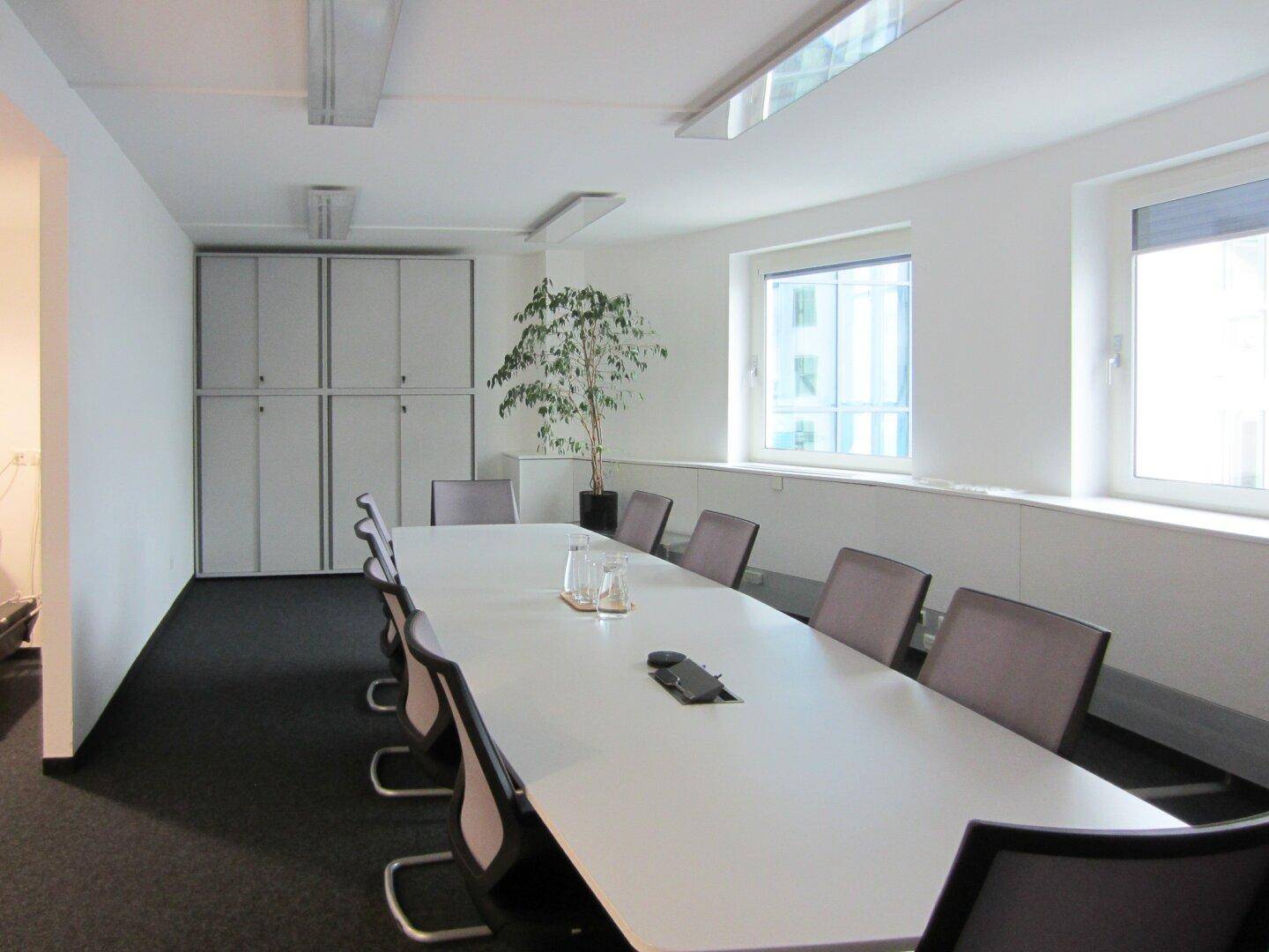 Konferenzraum mit langem Tisch, Stühlen und Schränken, ideal für Besprechungen und Präsentationen.