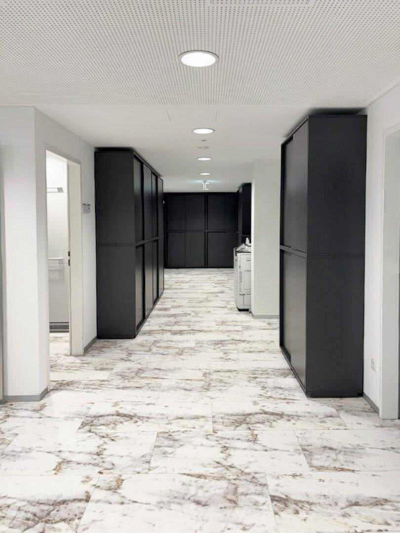 Heller Flur mit elegantem Marmor-ähnlichem Fliesenboden und praktischen schwarzen Einbauschränken.
