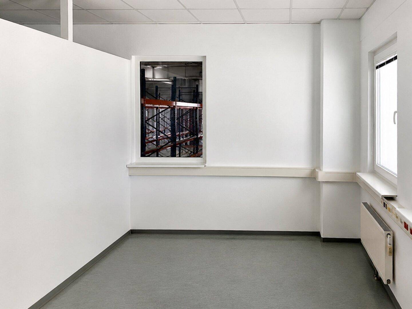 Helles Büro oder Arbeitszimmer mit weiß gestrichenen Wänden und Blick in ein Lager.