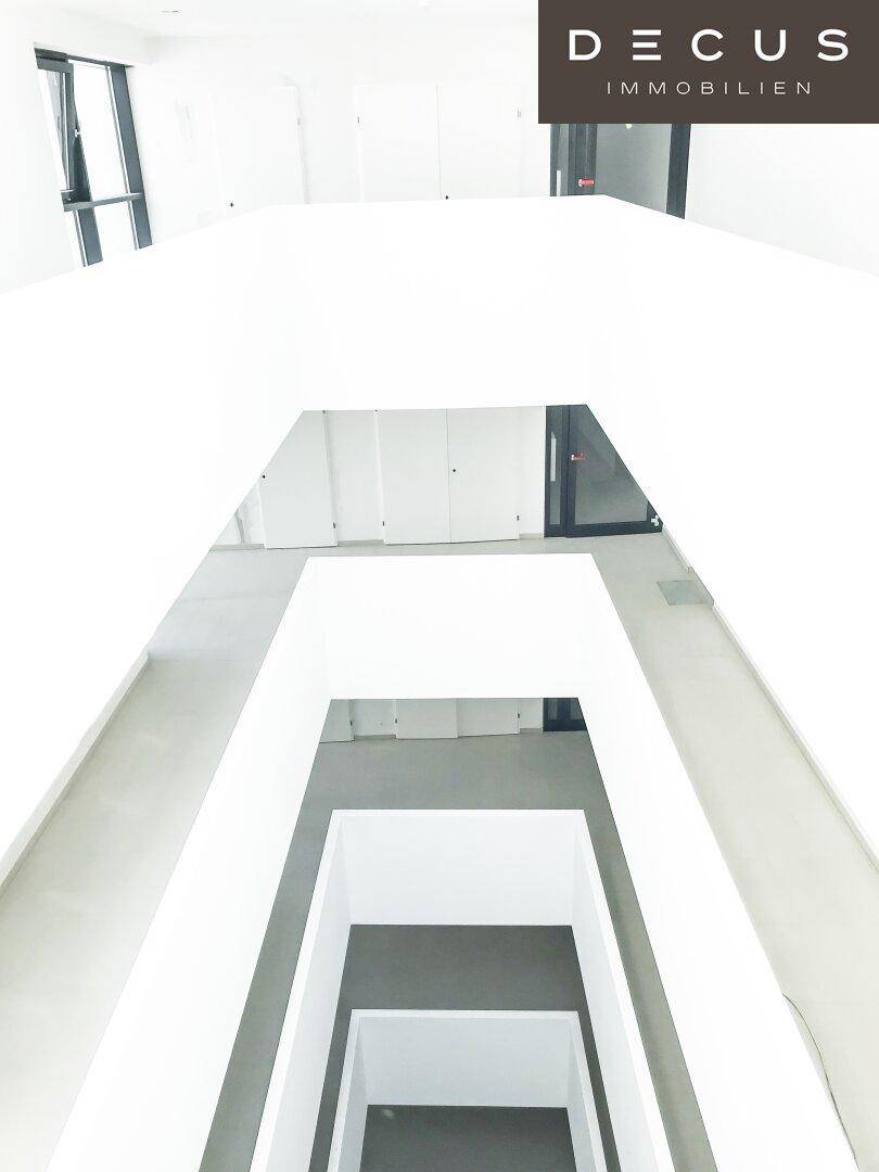 Heller Treppenhausbereich mit minimalistischem Design und Blick in die unteren Etagen.
