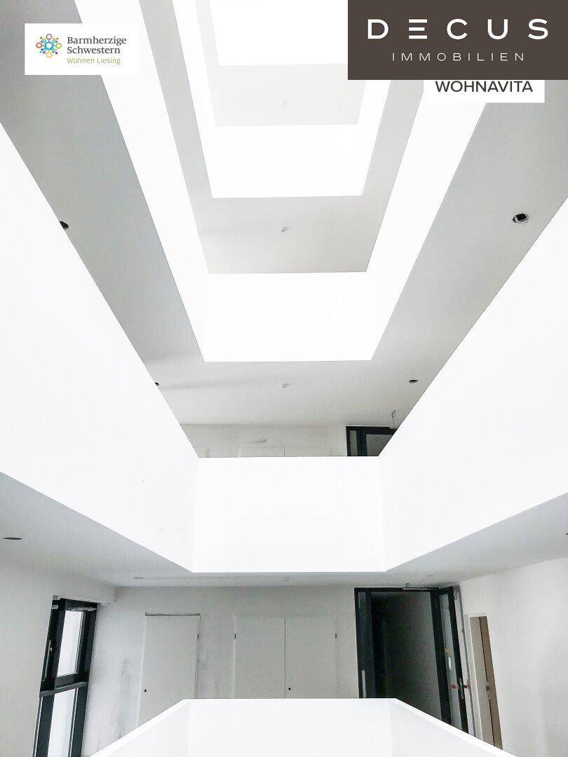 Lichtdurchfluteter Flur mit hoher Decke und großem Oberlicht, das viel Tageslicht spendet.