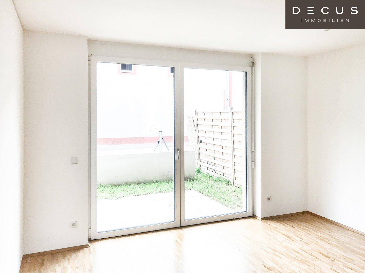 Lichtdurchfluteter Raum mit Parkettboden und Zugang zu einer kleinen Außenterrasse.