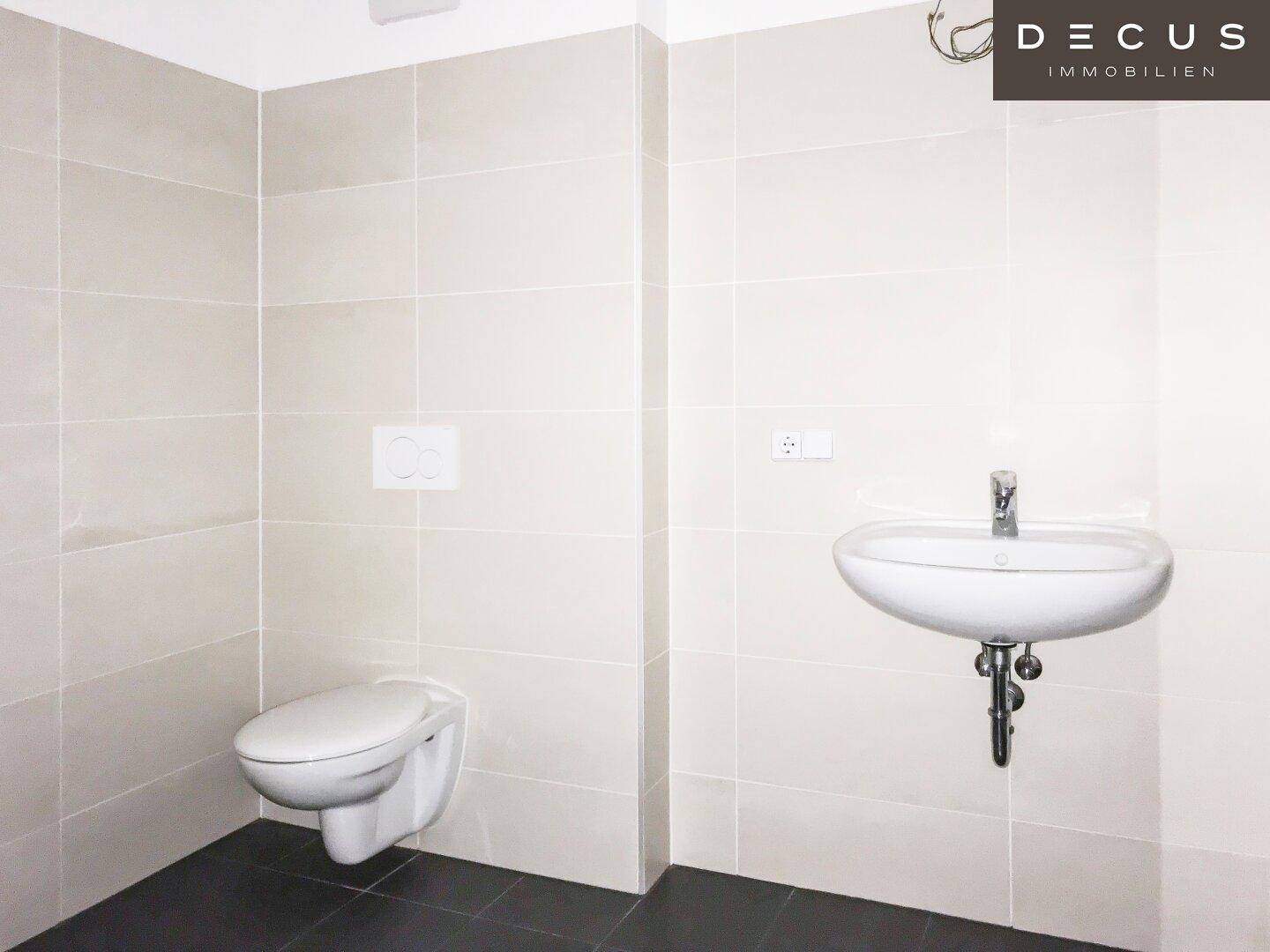 Badezimmer mit wandhängendem WC, Waschbecken und modernen Fliesen.