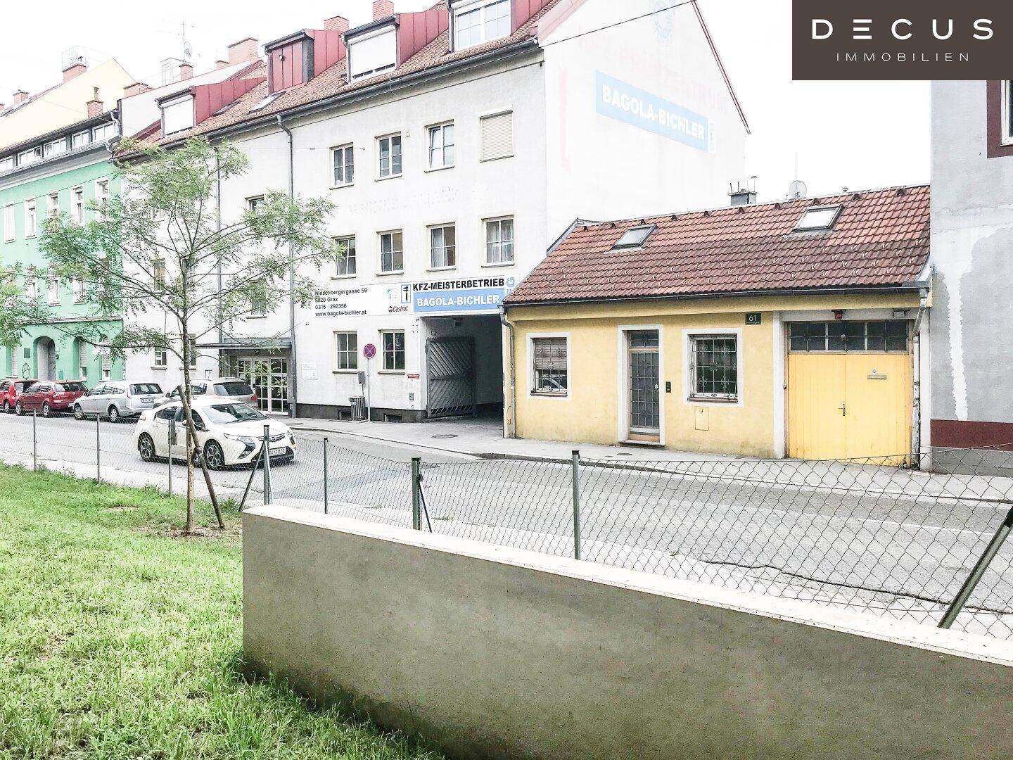 Blick auf eine belebte Straße mit historischen Gebäuden und parkenden Autos.