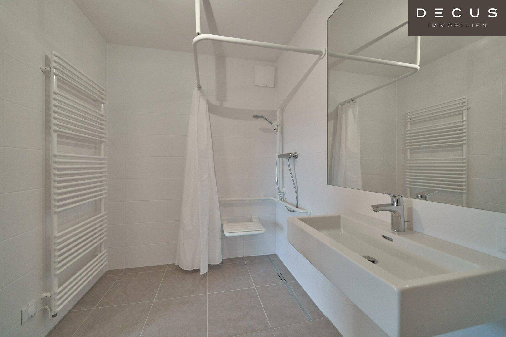 Modernes Badezimmer mit barrierefreier Dusche, Einzelwaschbecken und beheiztem Handtuchhalter.