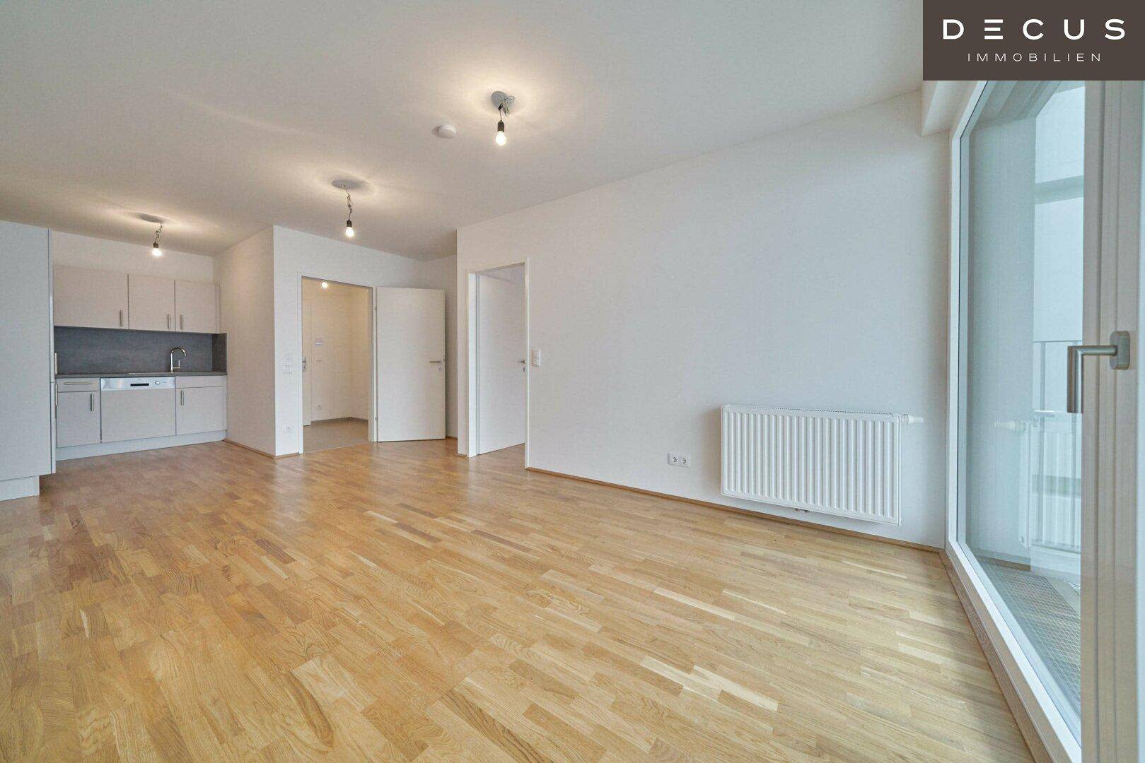 Geräumiger offener Wohnbereich mit integrierter Küche, Parkettboden und Heizkörper.
