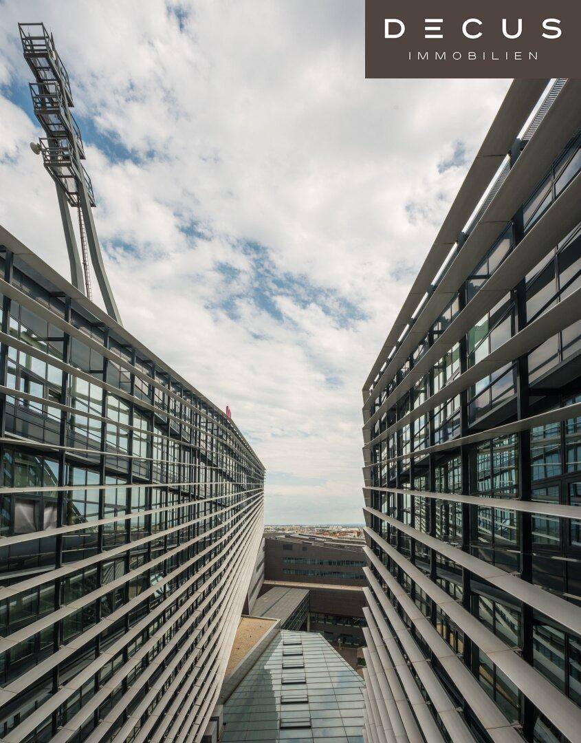 Vertikale Ansicht zwischen zwei modernen Gebäudeflügeln mit vielen Fenstern und Himmel.