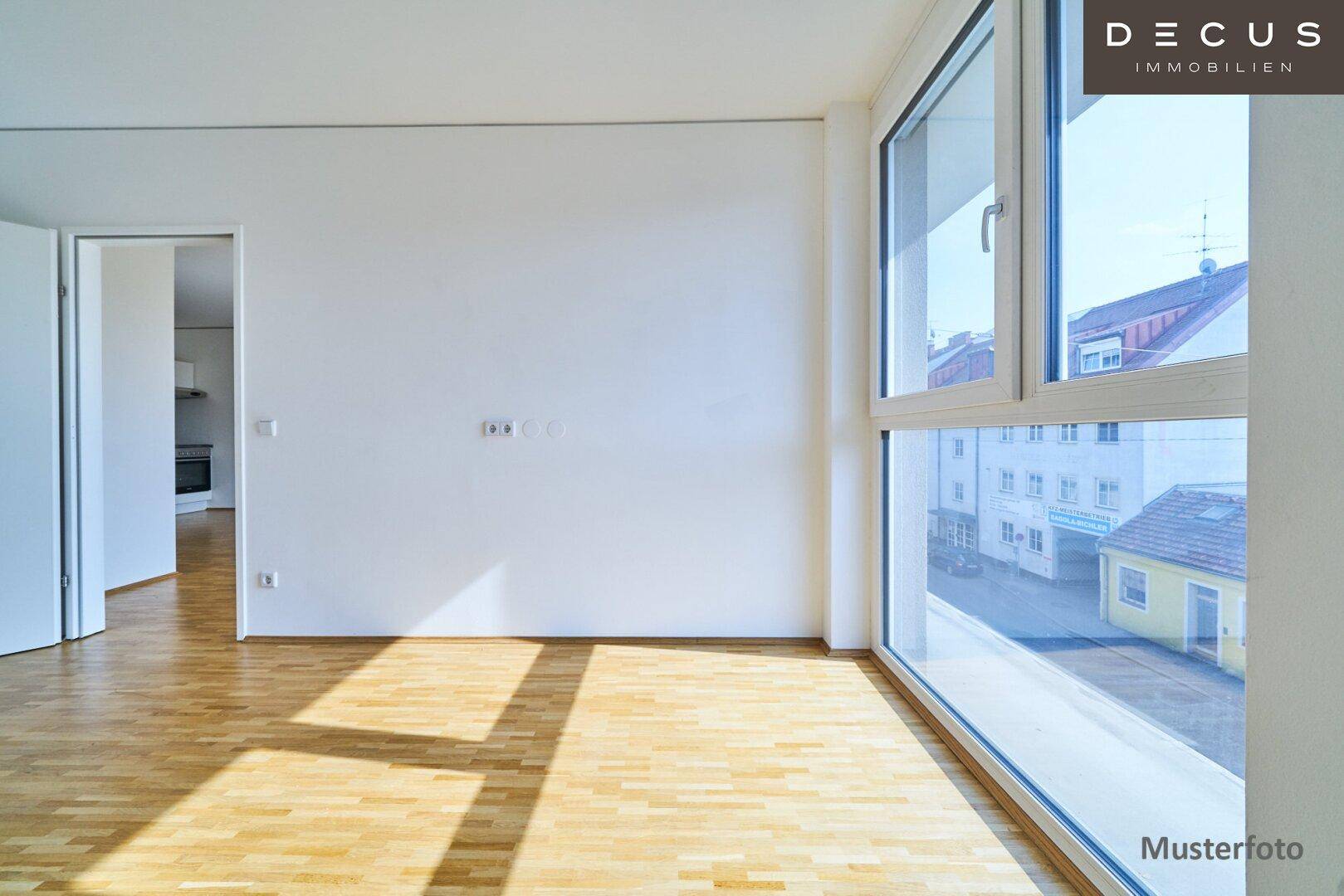 Helles Zimmer mit Parkettboden und Blick auf die umliegende Bebauung durch große Fenster.
