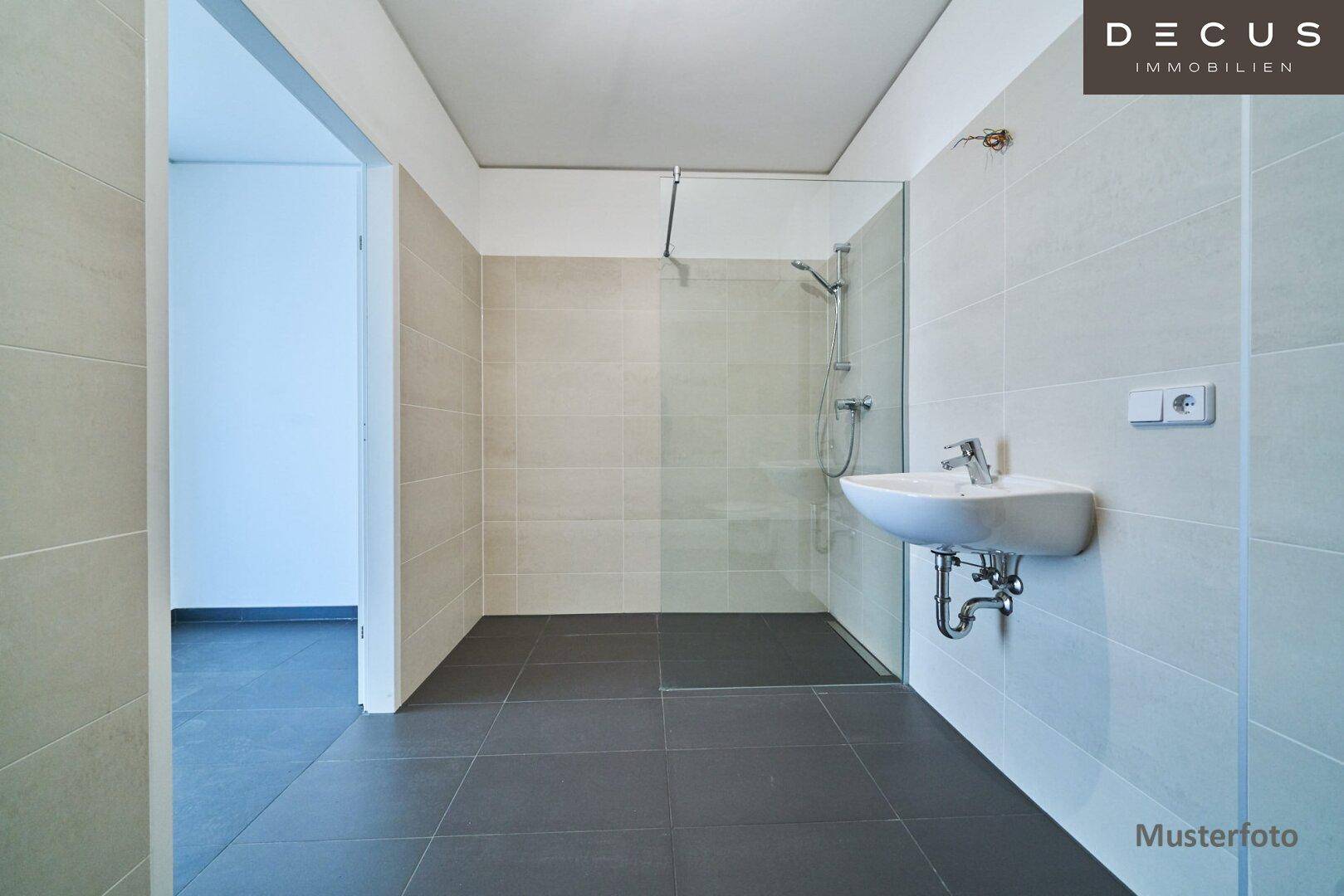 Geräumiges Badezimmer mit moderner Dusche und Waschbecken, bereit für die Einrichtung.