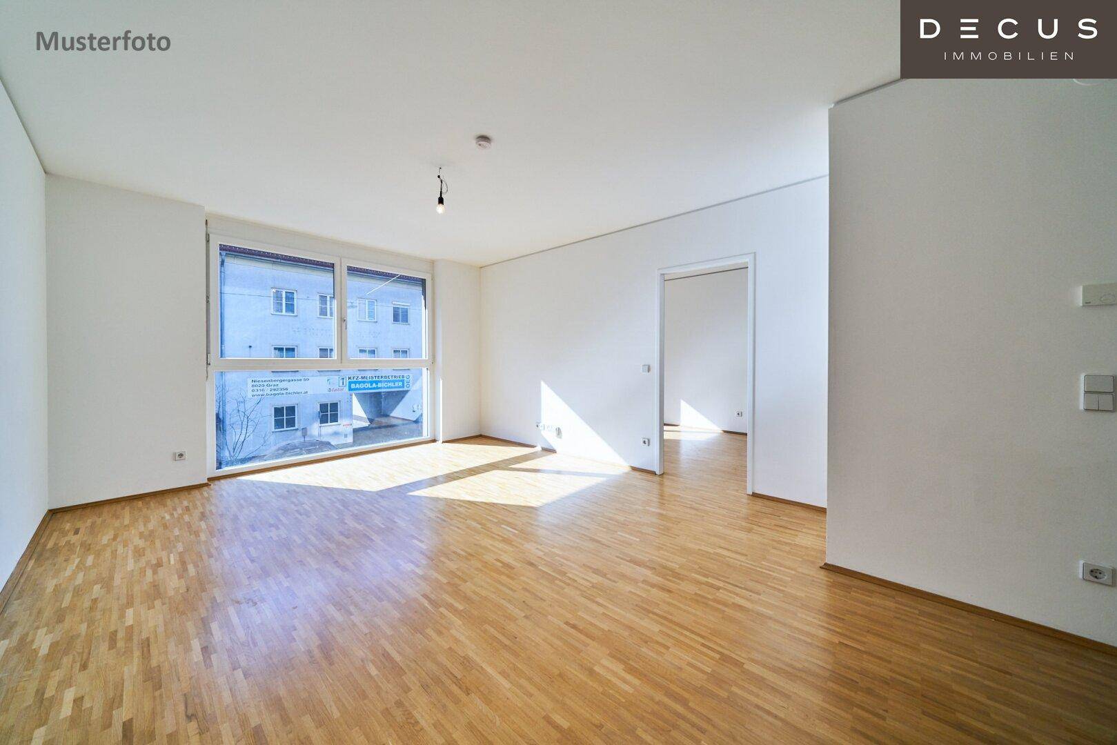 Geräumiges Wohnzimmer mit hellem Parkettboden und großen Fenstern, die den Raum erhellen.