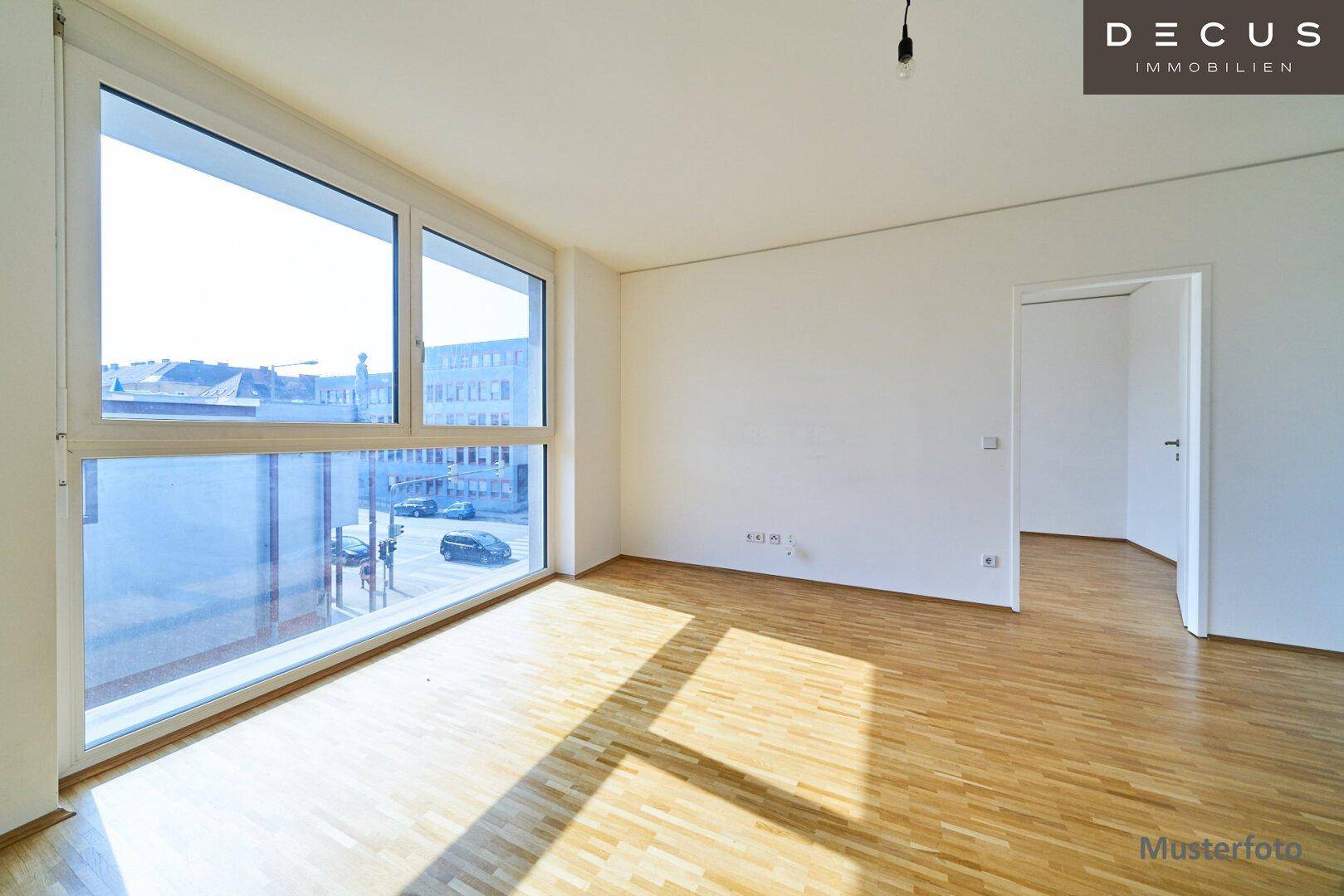 Lichtdurchflutetes Zimmer mit Parkettboden und weitem Blick durch die großen Fenster.