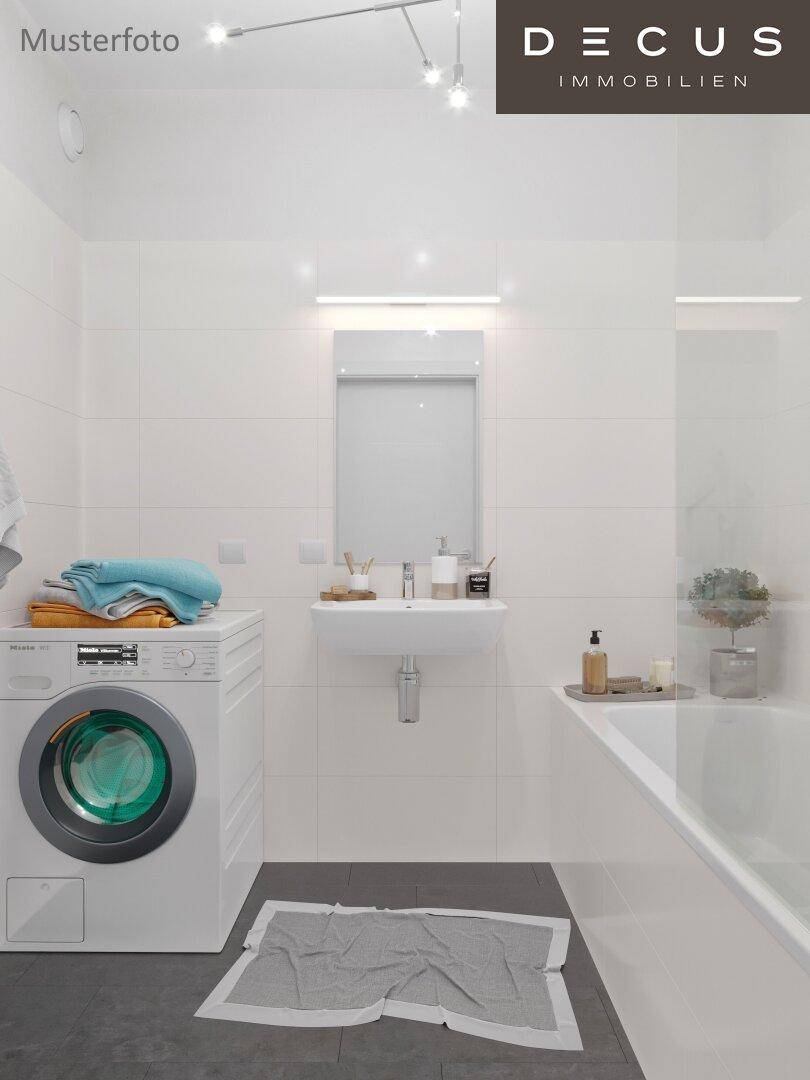 Modernes Badezimmer mit Badewanne, Waschbecken, Waschmaschine und weißen Fliesen.