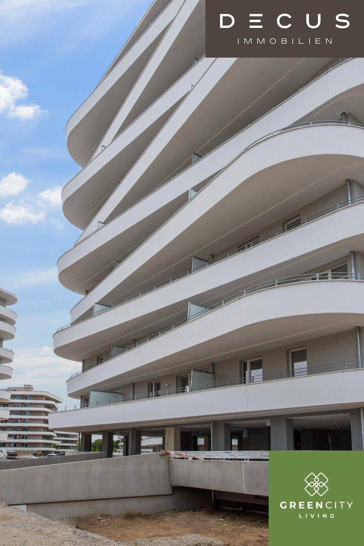 Moderne Architektur eines Wohngebäudes mit geschwungenen Balkonen und einer hellen Fassade unter blauem Himmel.