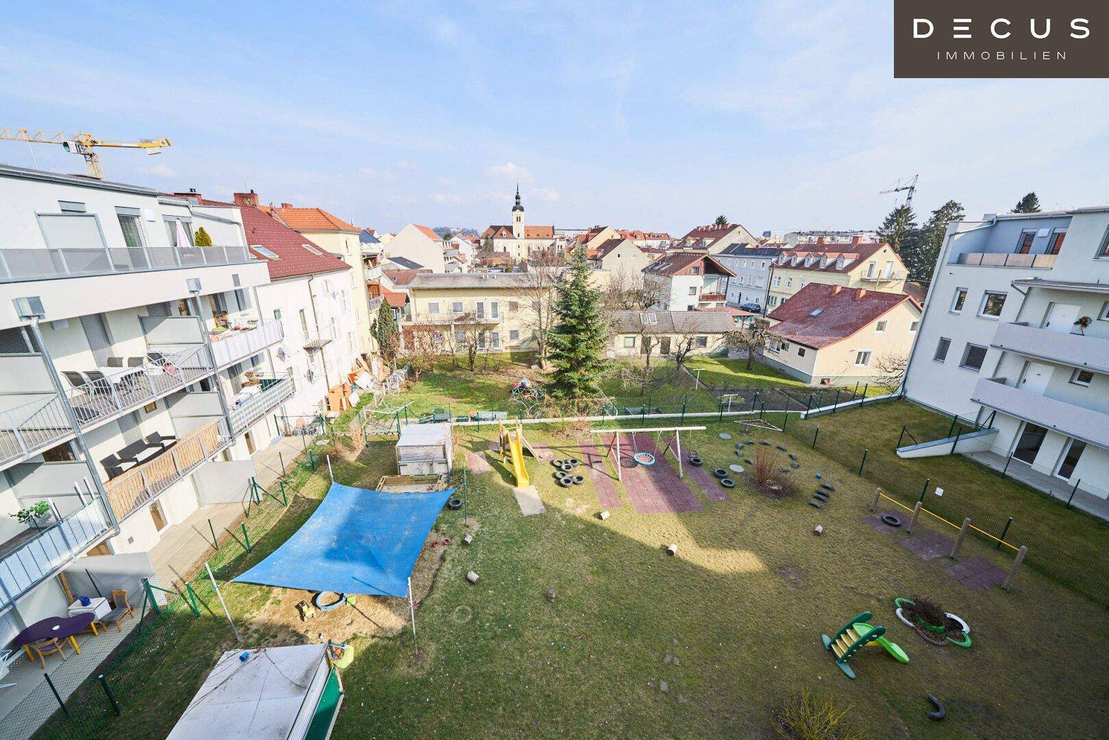 Großer gemeinschaftlicher Gartenbereich mit Spielgeräten, umgeben von Wohngebäuden.