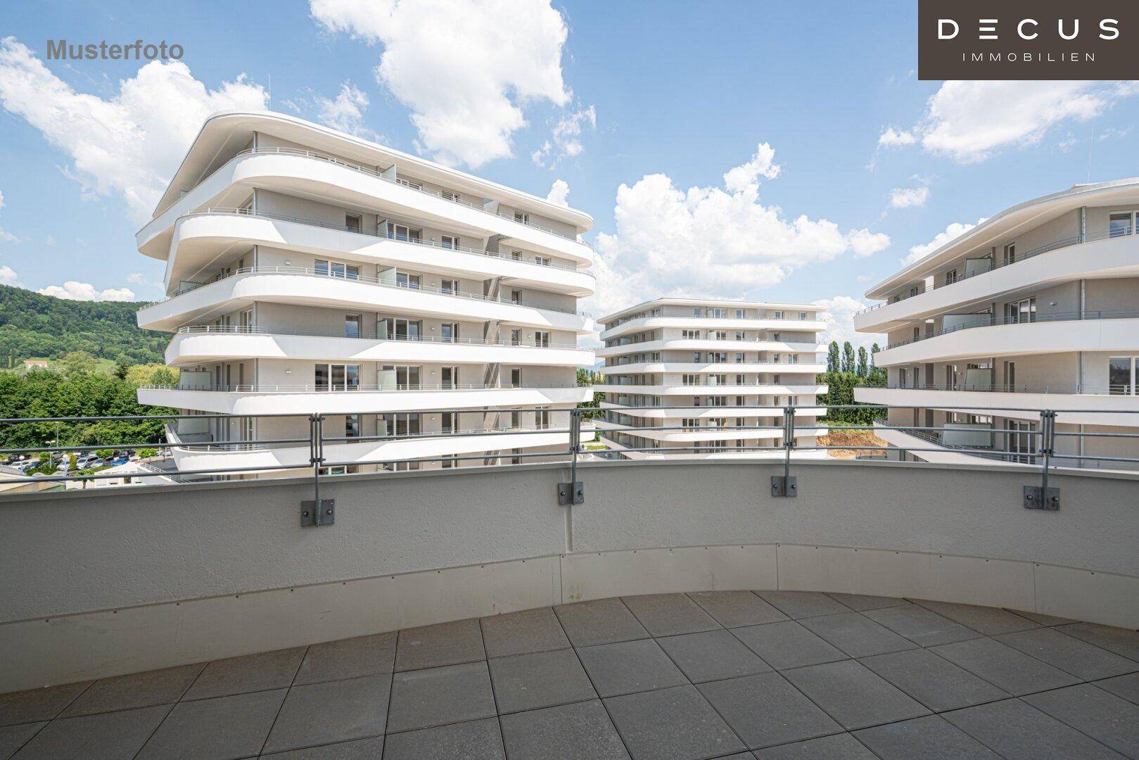 Große Außenterrasse mit Fliesenboden und Blick auf moderne Wohngebäude.