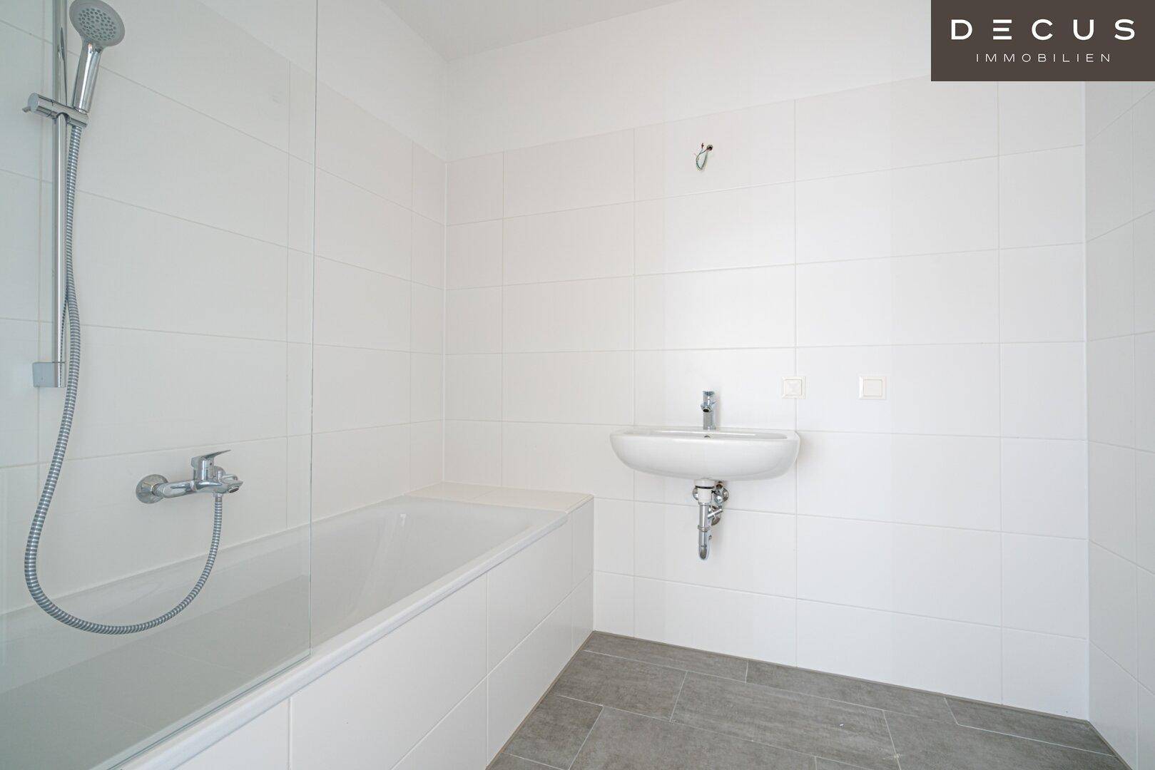 Modernes Badezimmer mit weißen Fliesen, Badewanne und Waschbecken.