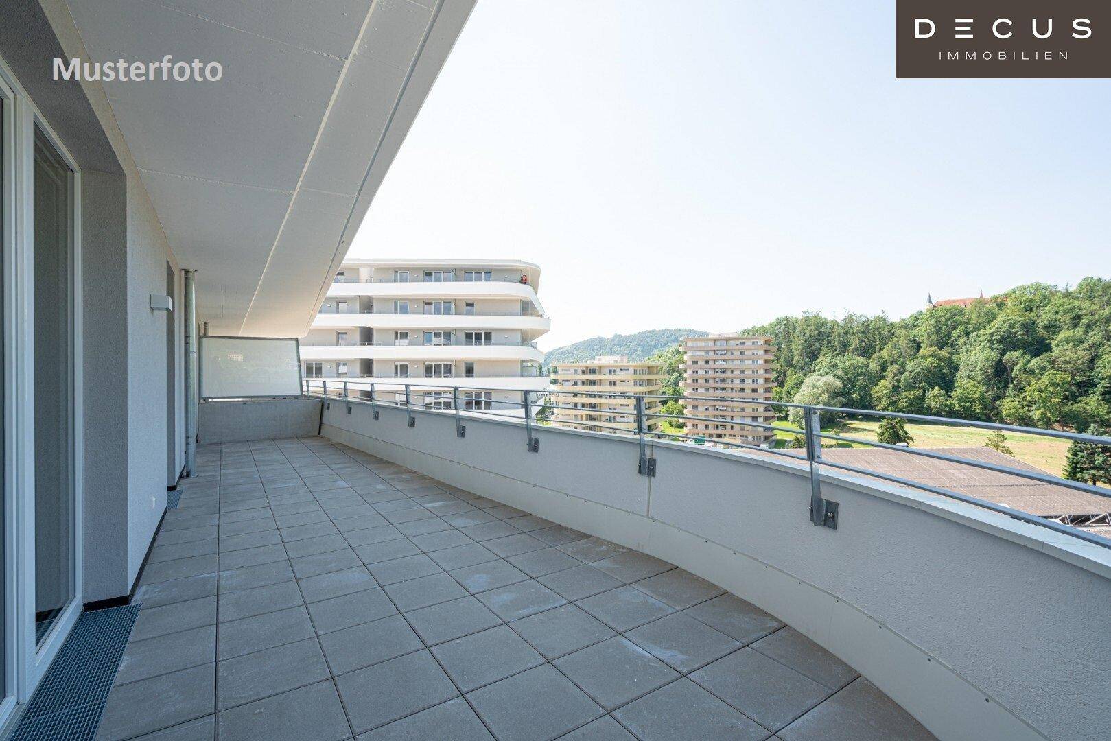 Große, geflieste Terrasse mit Blick auf moderne Wohngebäude und grüne Umgebung.