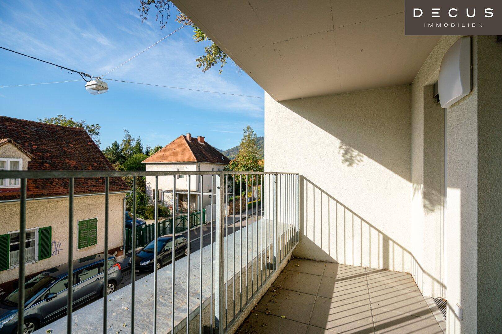 Kleiner Balkon mit Fliesenboden und Blick auf die umliegende Wohngegend und Bäume.