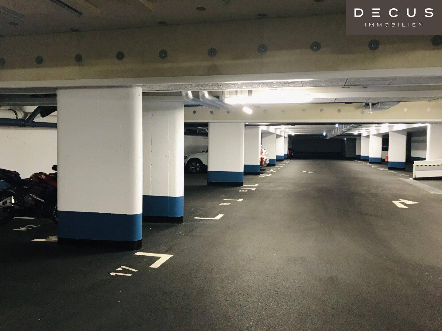 Ansicht der Tiefgarage mit vielen markierten Stellplätzen und einer Reihe von tragenden Säulen.