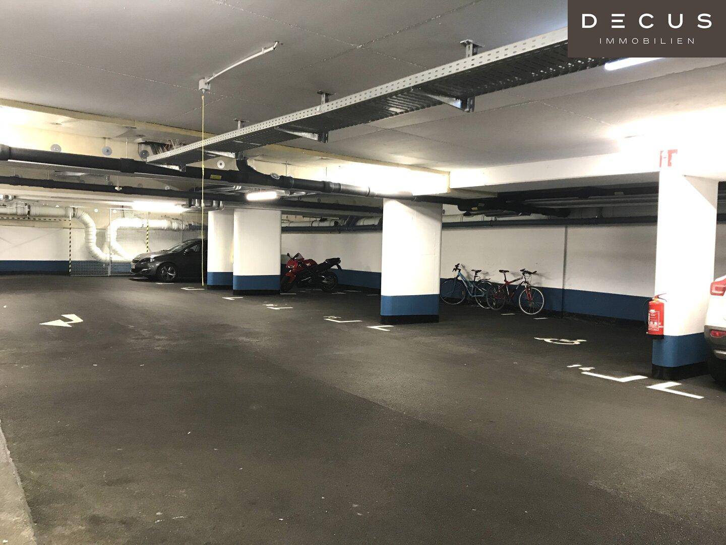 Weitere Ansicht der Tiefgarage mit geparkten Fahrzeugen und Fahrrädern, gut beleuchtet und organisiert.