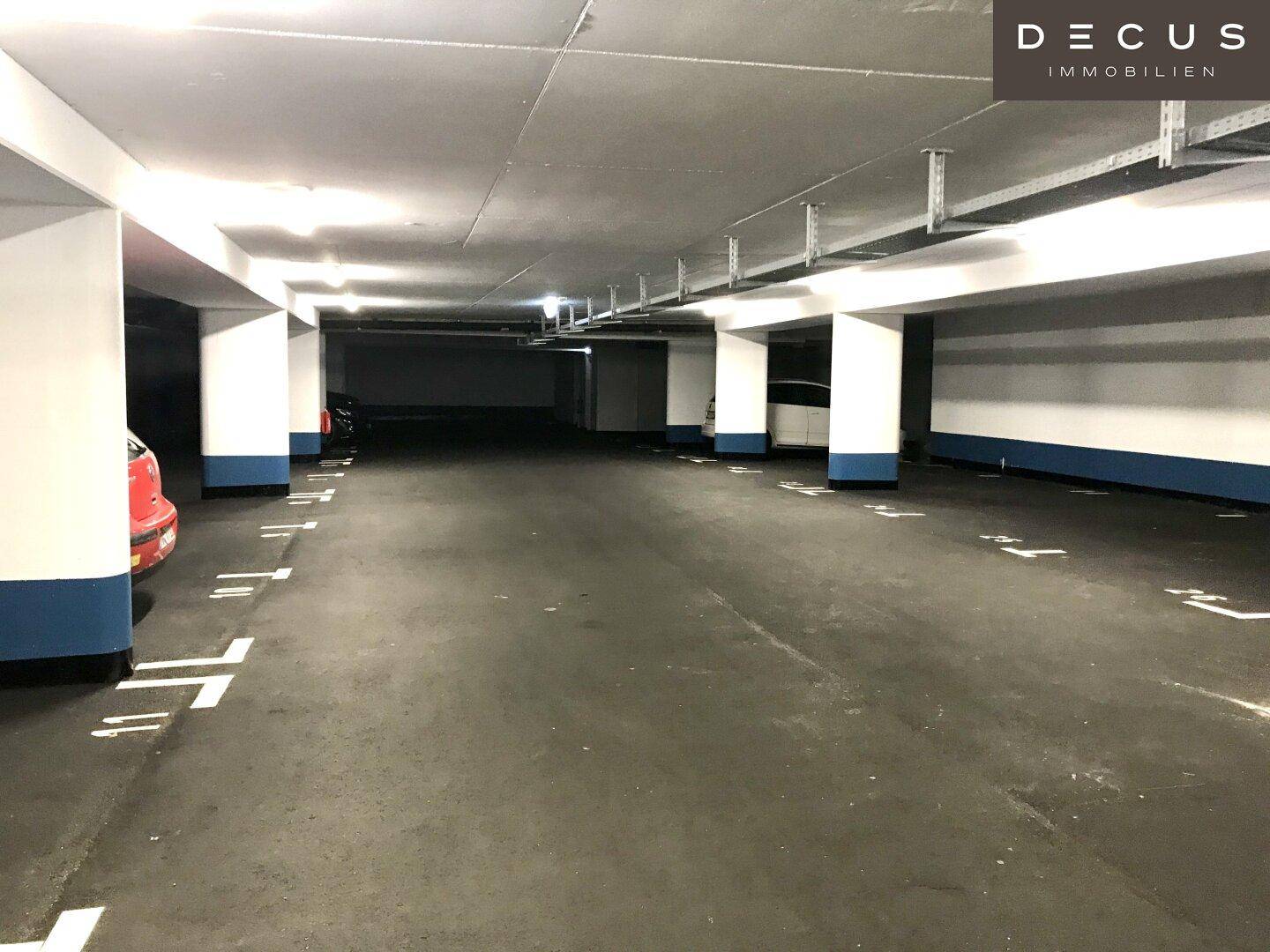 Weitläufige Tiefgarage mit zahlreichen leeren Stellplätzen und tragenden Säulen, gut ausgeleuchtet.