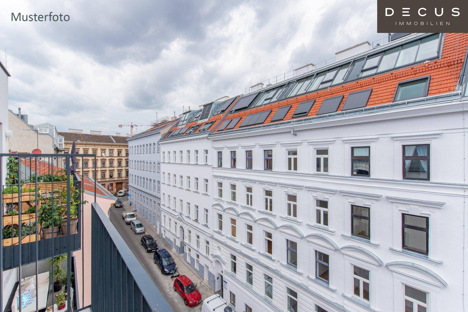 Blick von einem Balkon auf eine belebte Straße mit parkenden Autos und gegenüberliegenden Gebäuden.