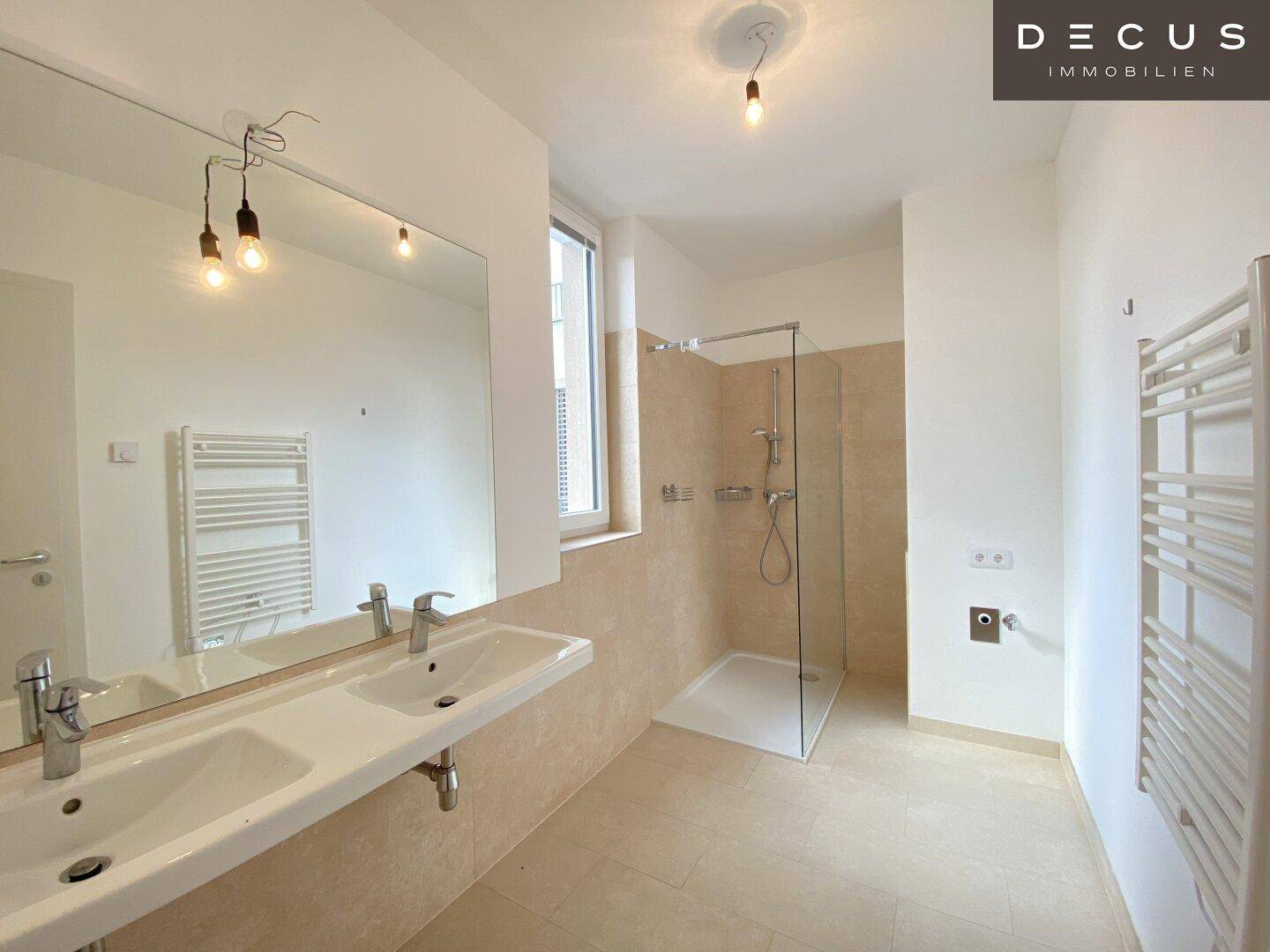 Modernes Badezimmer mit Doppelwaschbecken, großer Dusche und beheiztem Handtuchhalter.