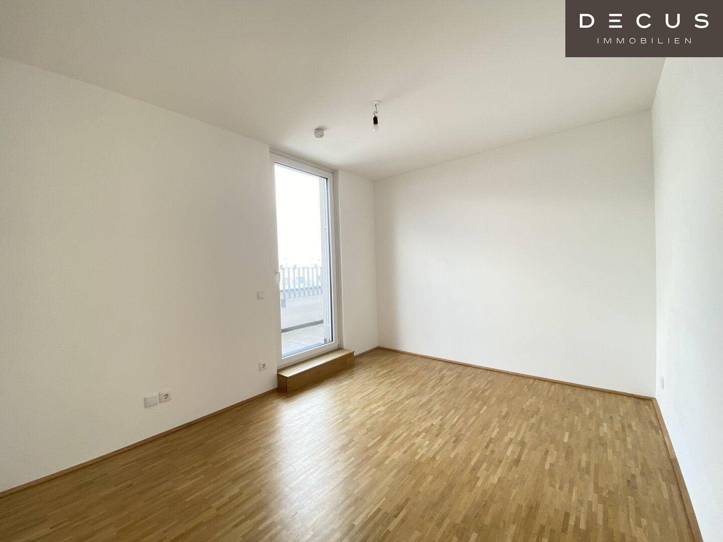 Helles Schlafzimmer mit Parkettboden und direktem Zugang zu einem Außenbereich.