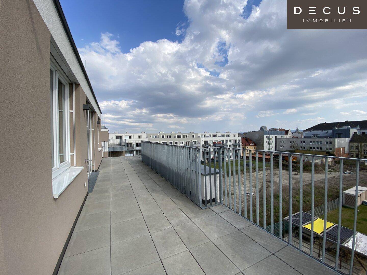 Weitläufige Dachterrasse mit Fliesenboden und Blick auf die umliegende Bebauung.