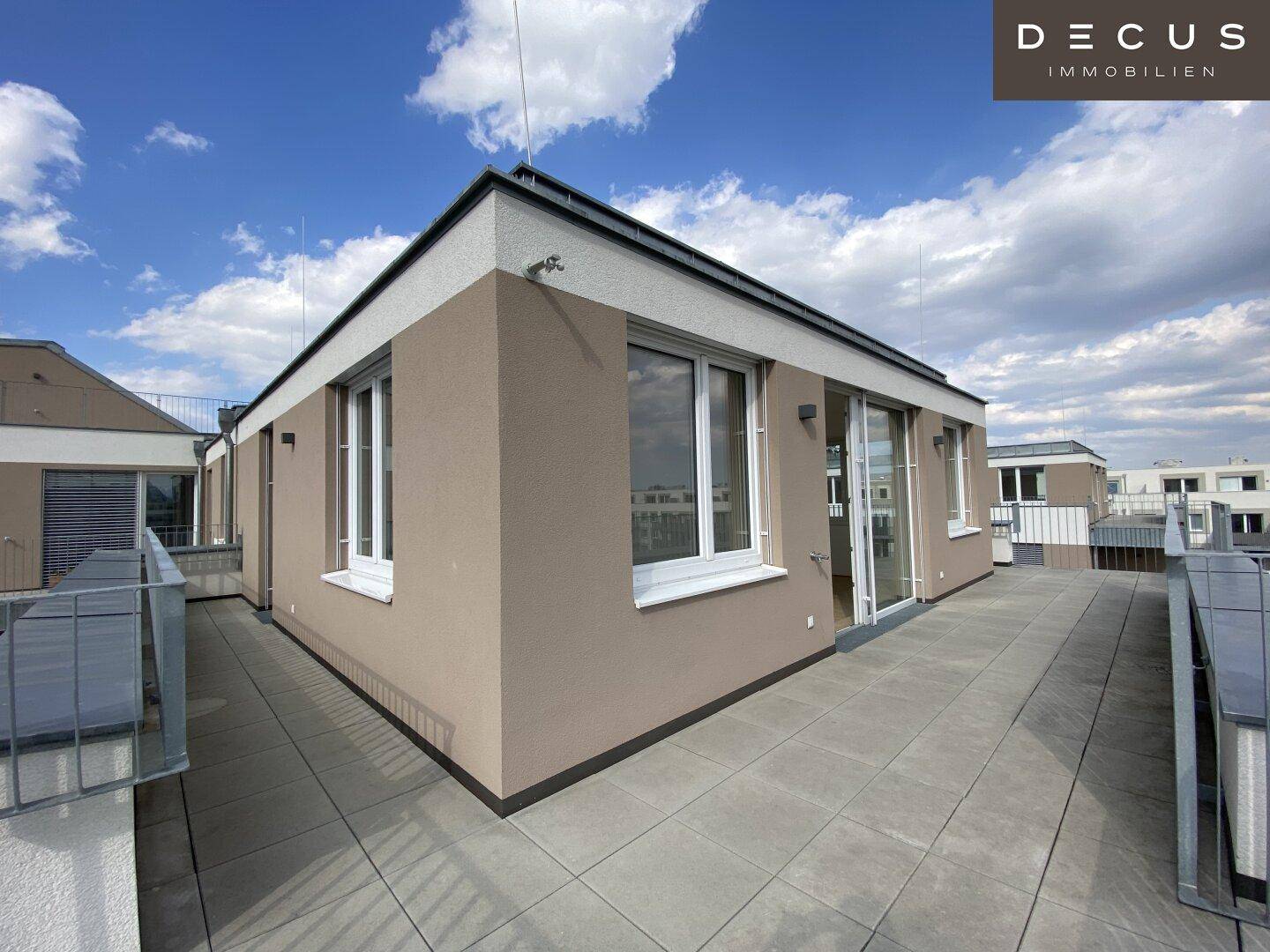 Moderne Architektur mit großen Fenstern und einer weitläufigen Terrasse auf dem Dach.