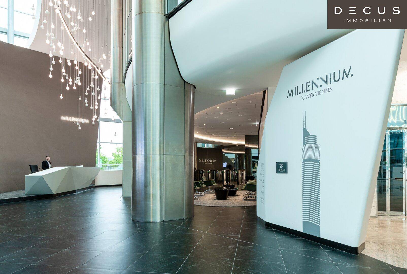 Moderne und luxuriöse Lobby mit hoher Decke, stilvoller Rezeption und eleganten Beleuchtungselementen.