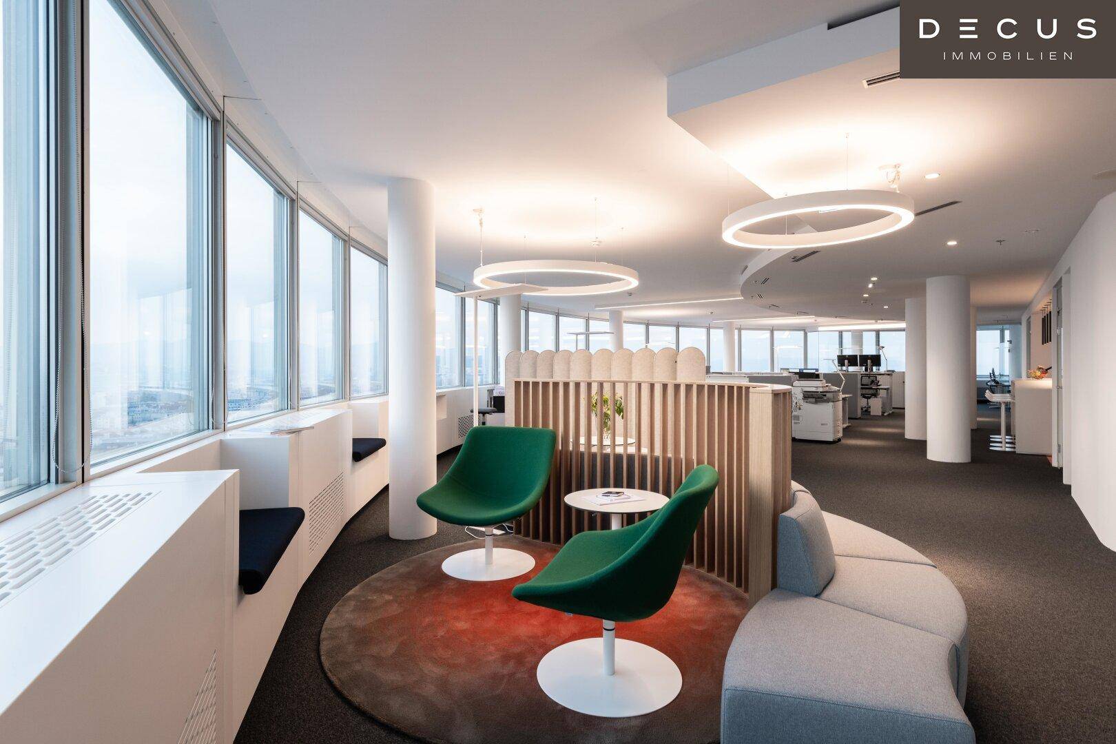 Helles und modernes Büro mit großen Fenstern, zeitgenössischen Möbeln und offener Raumgestaltung.